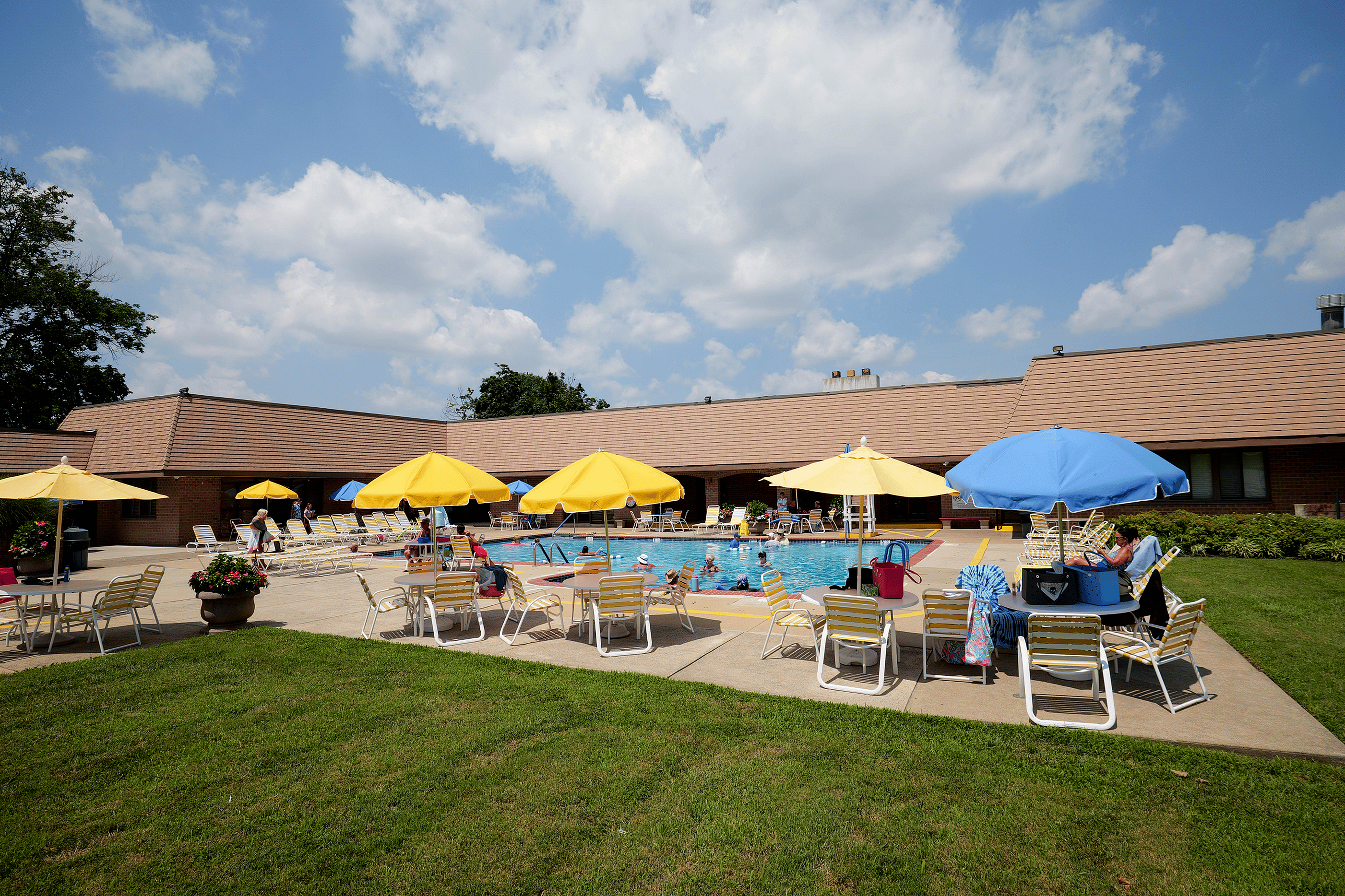 Inviting outdoor pool area with vibrant yellow umbrellas and comfortable seating, perfect for relaxation and socializing under a sunny blue sky.