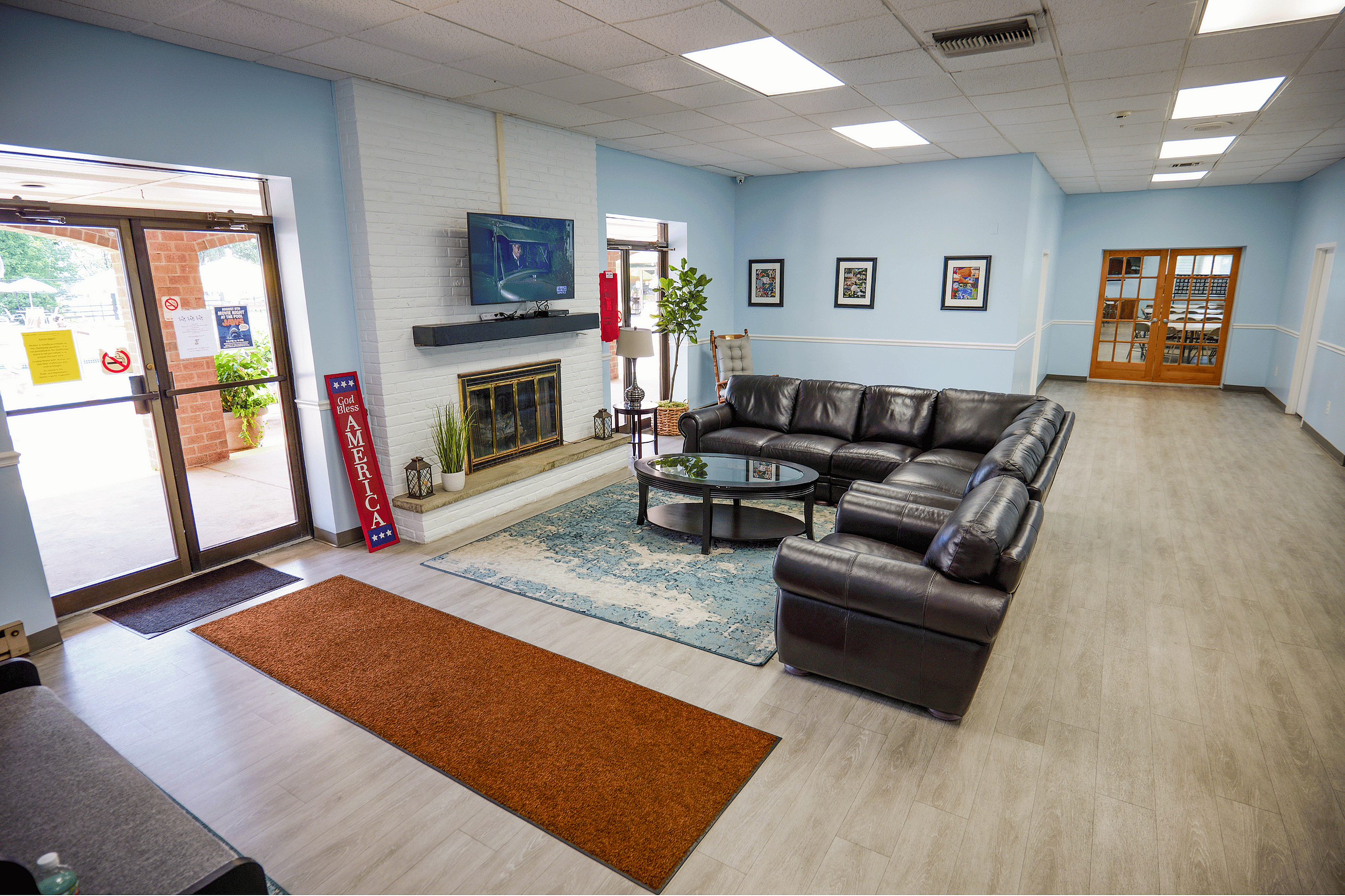 Inviting community lounge with sleek leather seating, a cozy fireplace, and natural light streaming through large windows.
