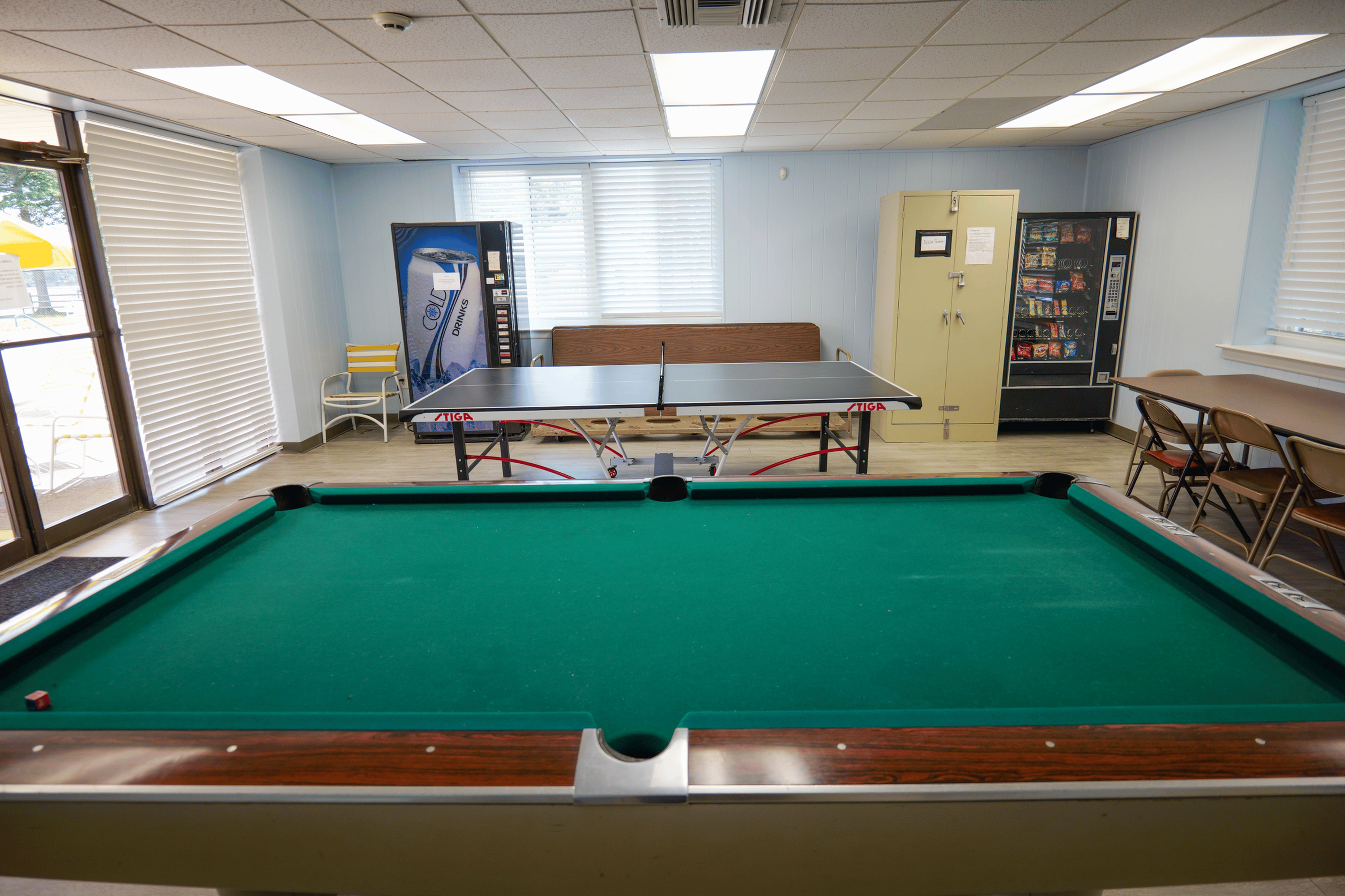 Vibrant recreational room featuring a pool table, ping pong table, and snack vending machines, perfect for fun and relaxation.