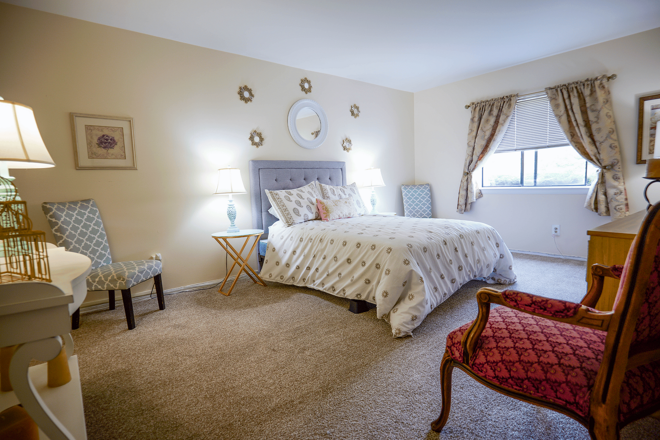 Cozy bedroom with a luxurious queen-sized bed, elegant decor, and natural light streaming through large windows, creating a serene retreat.