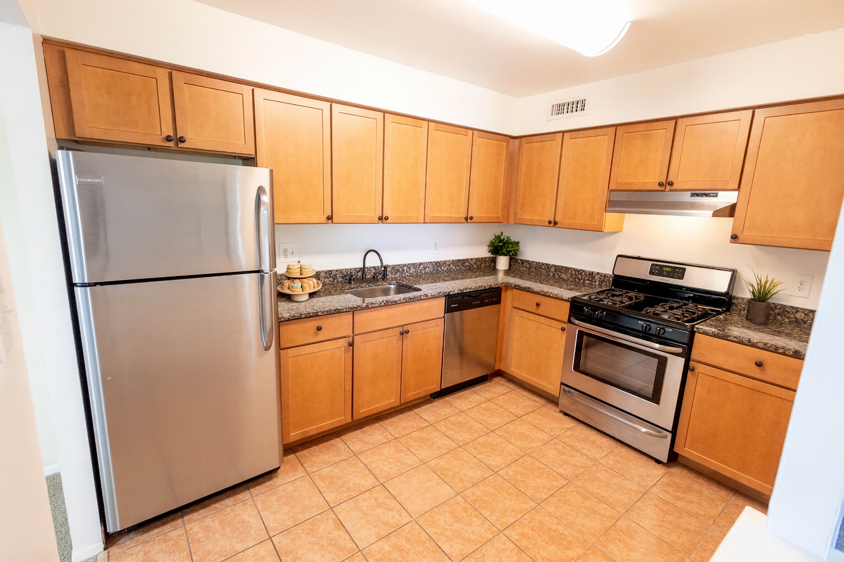 Spacious kitchen with sleek stainless steel appliances, elegant wooden cabinets, and granite countertops.