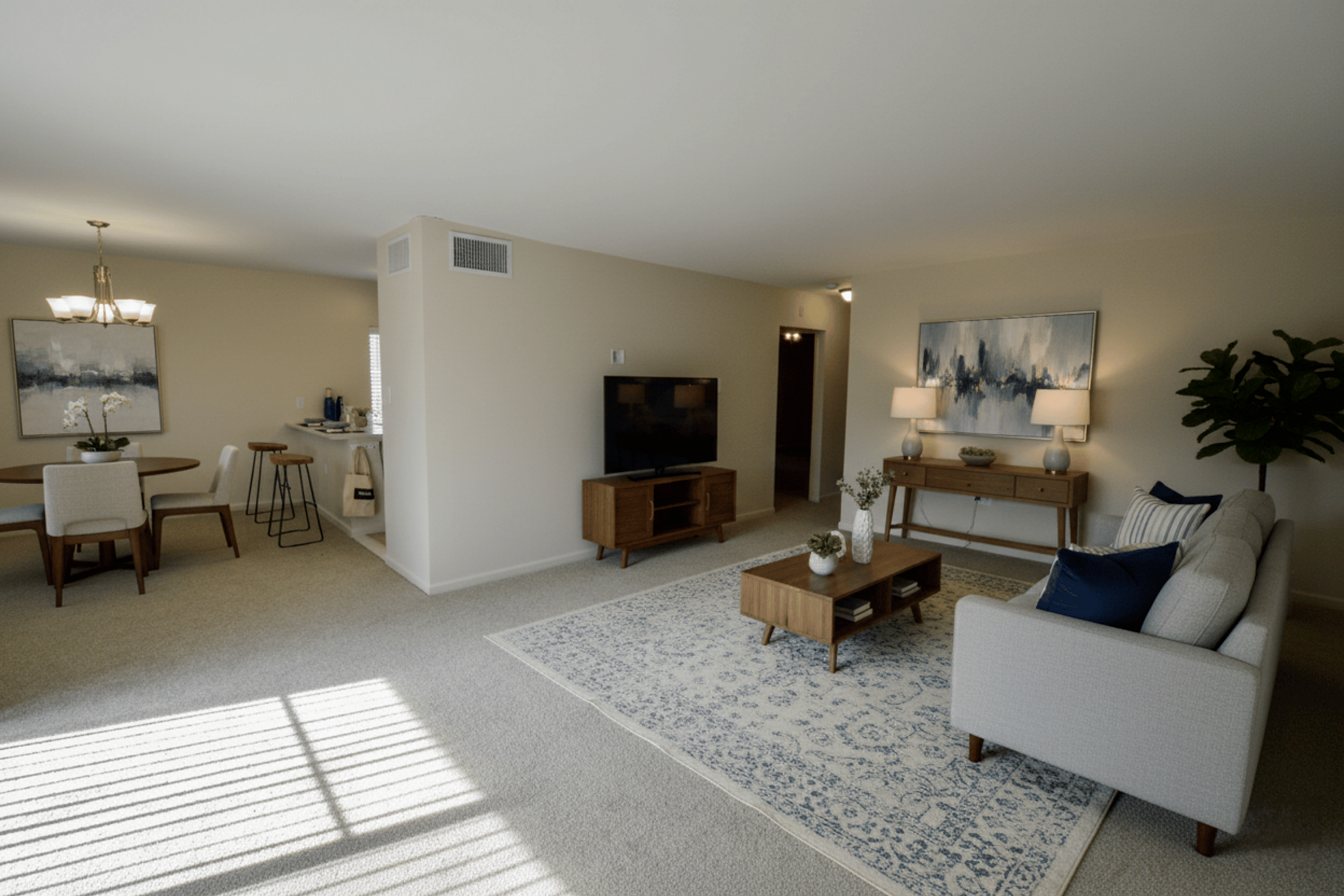 Inviting living room with stylish decor, featuring a cozy beige sofa, chic wooden furniture, elegant lighting, and a tranquil dining area.