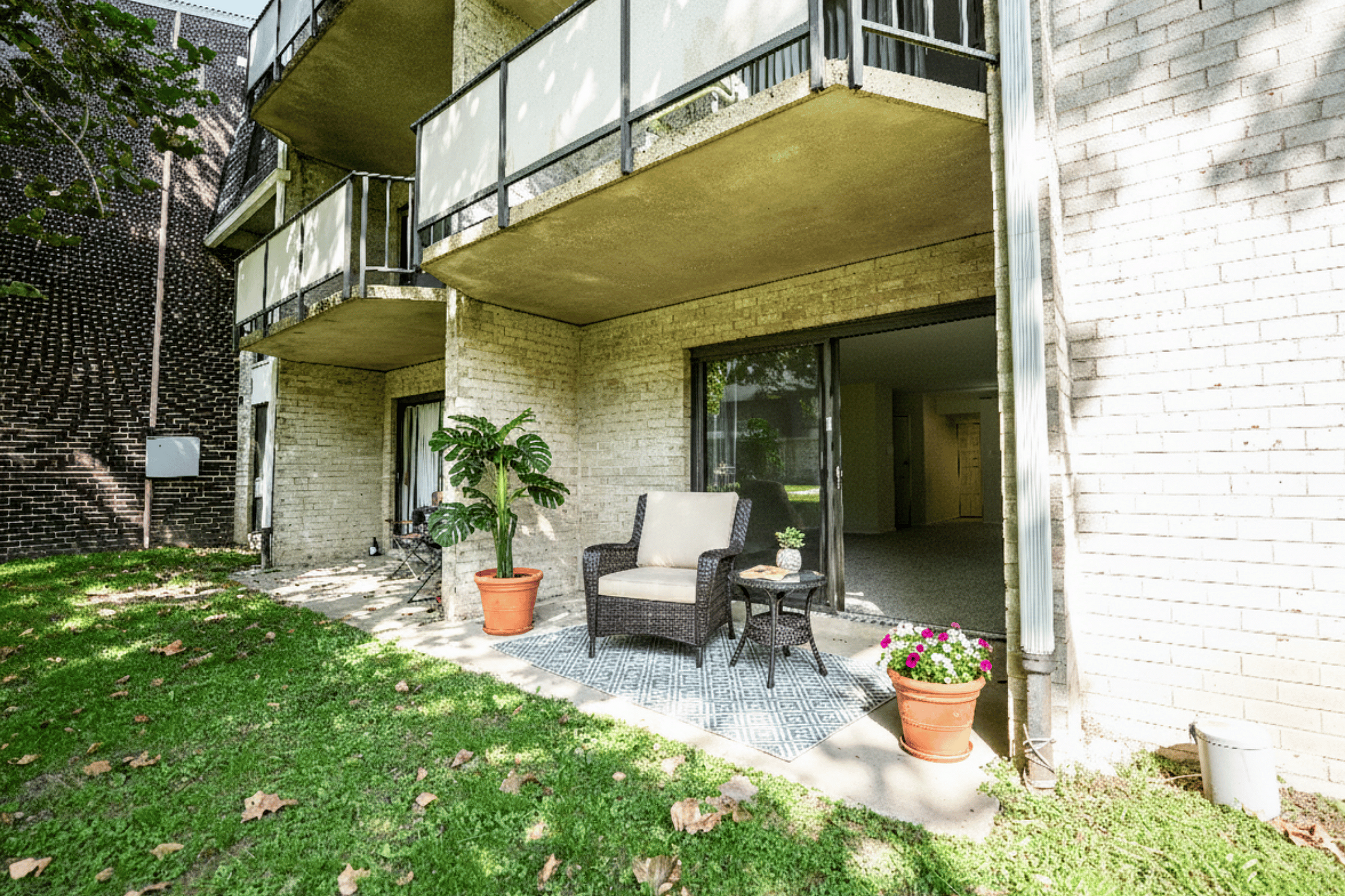 Charming apartment patio with cozy seating, vibrant plants, and lush greenery for a serene outdoor experience.