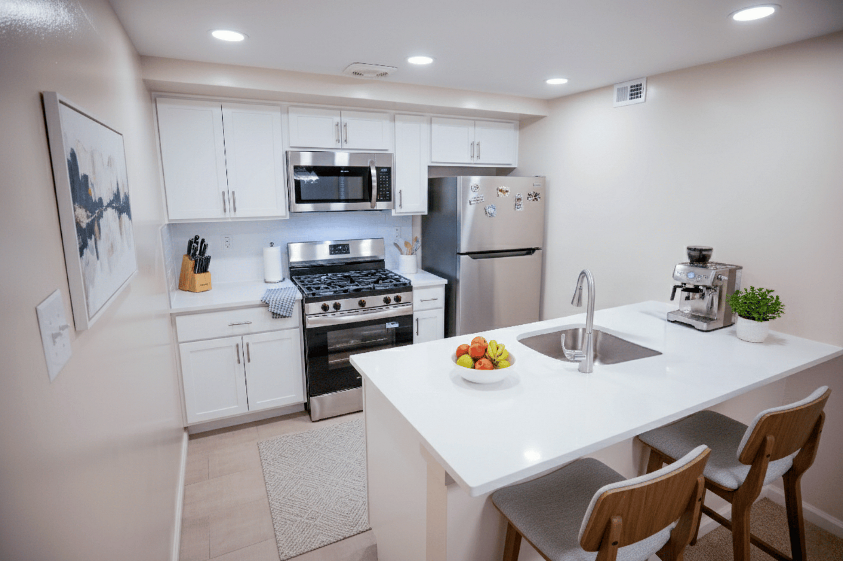 Modern kitchen with sleek white cabinetry, stainless steel appliances, and cozy seating island.