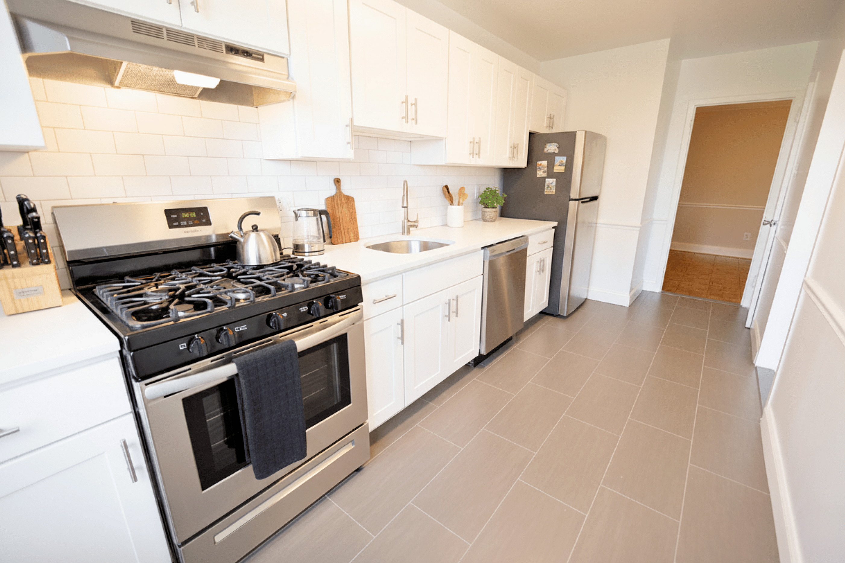 Bright and modern kitchen with stainless steel appliances, sleek countertops, and tile flooring, perfect for culinary enthusiasts.