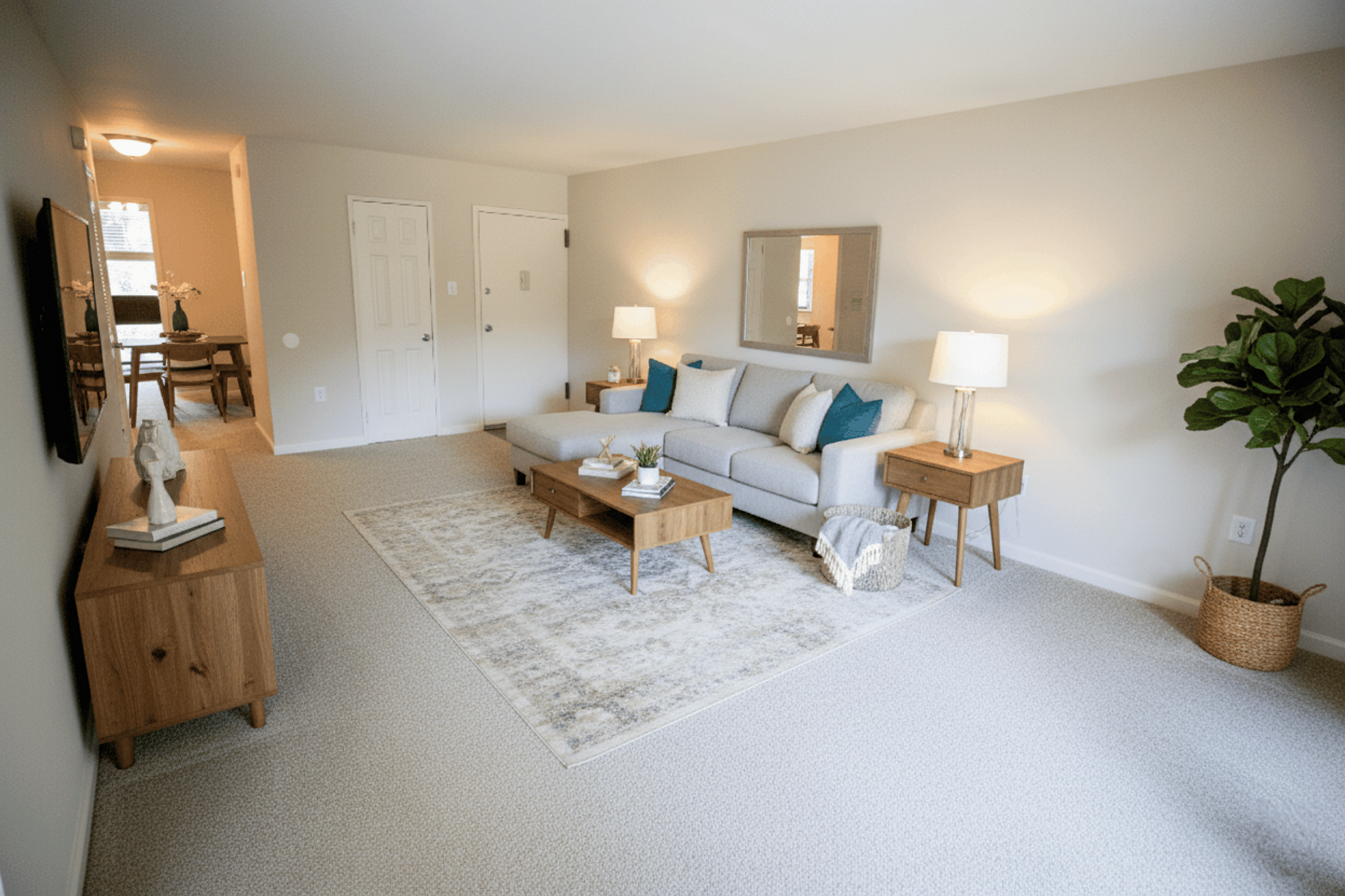 Welcoming living room with elegant decor, featuring a cozy gray sectional sofa, wooden accents, and abundant natural light.