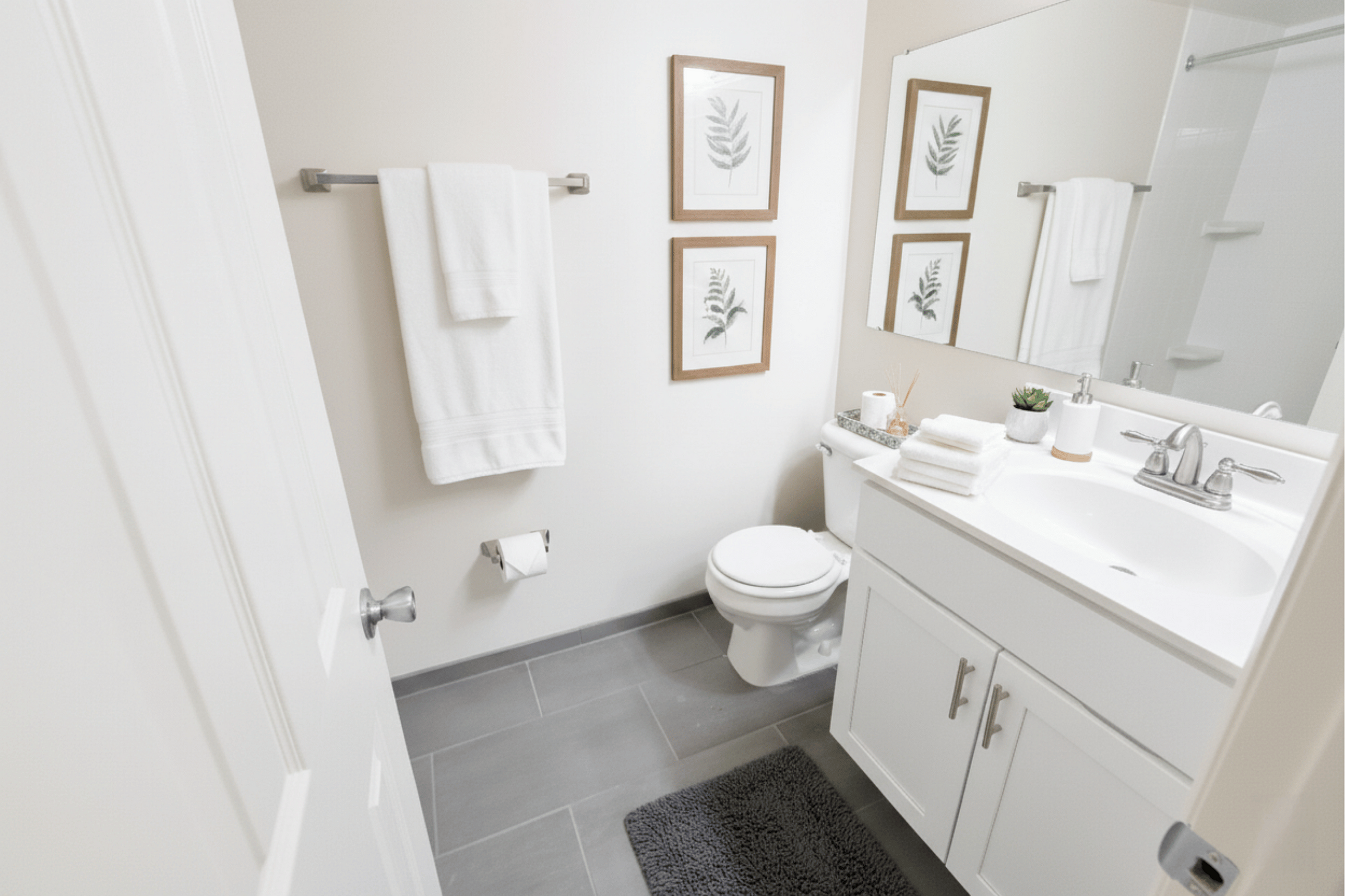 Elegant bathroom featuring modern fixtures, pristine white cabinetry, and tasteful botanical wall art, offering a serene and stylish retreat.