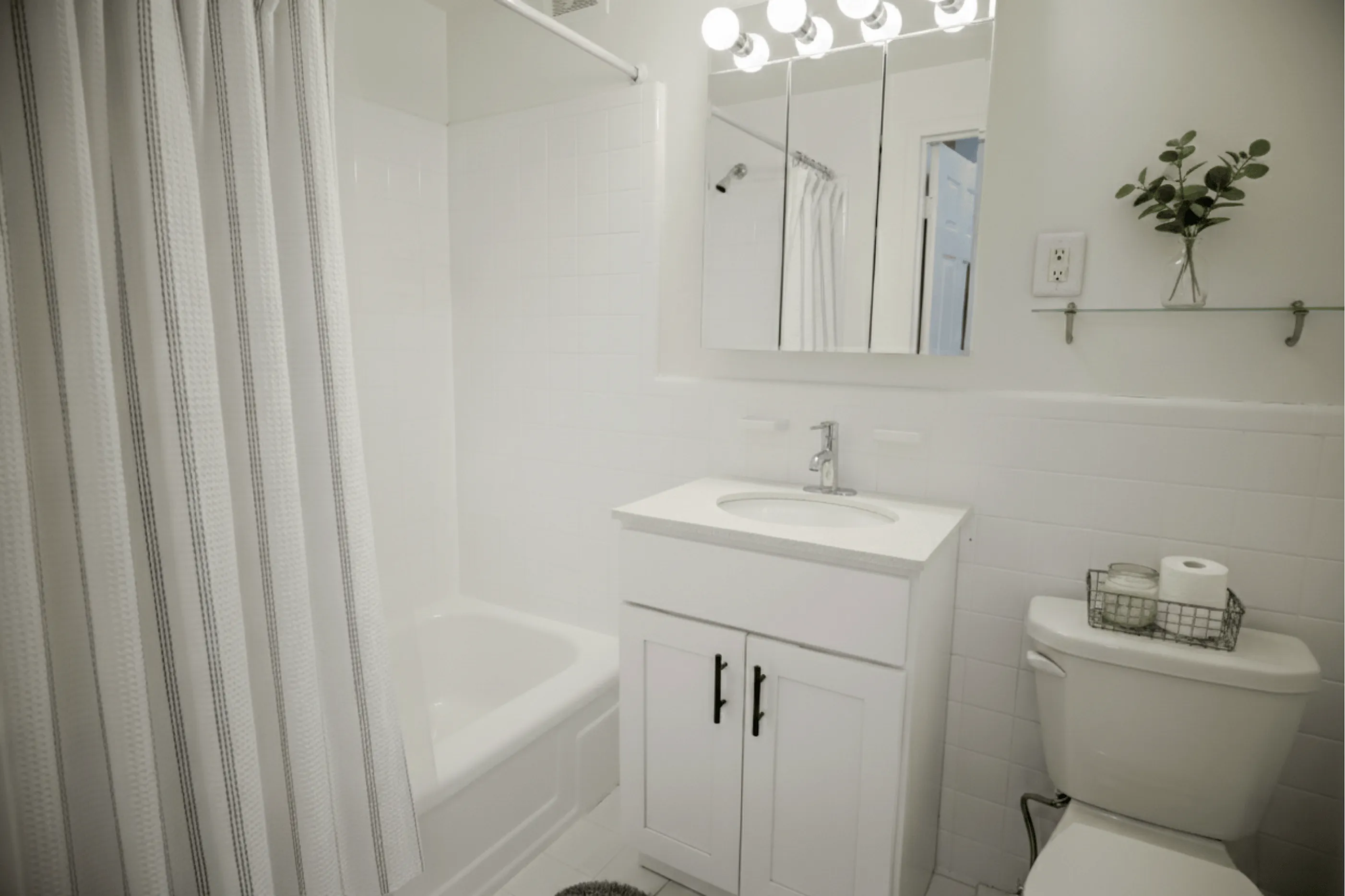 Elegant bathroom with clean white tiles, a sleek vanity, and modern lighting, offering a fresh and inviting atmosphere.