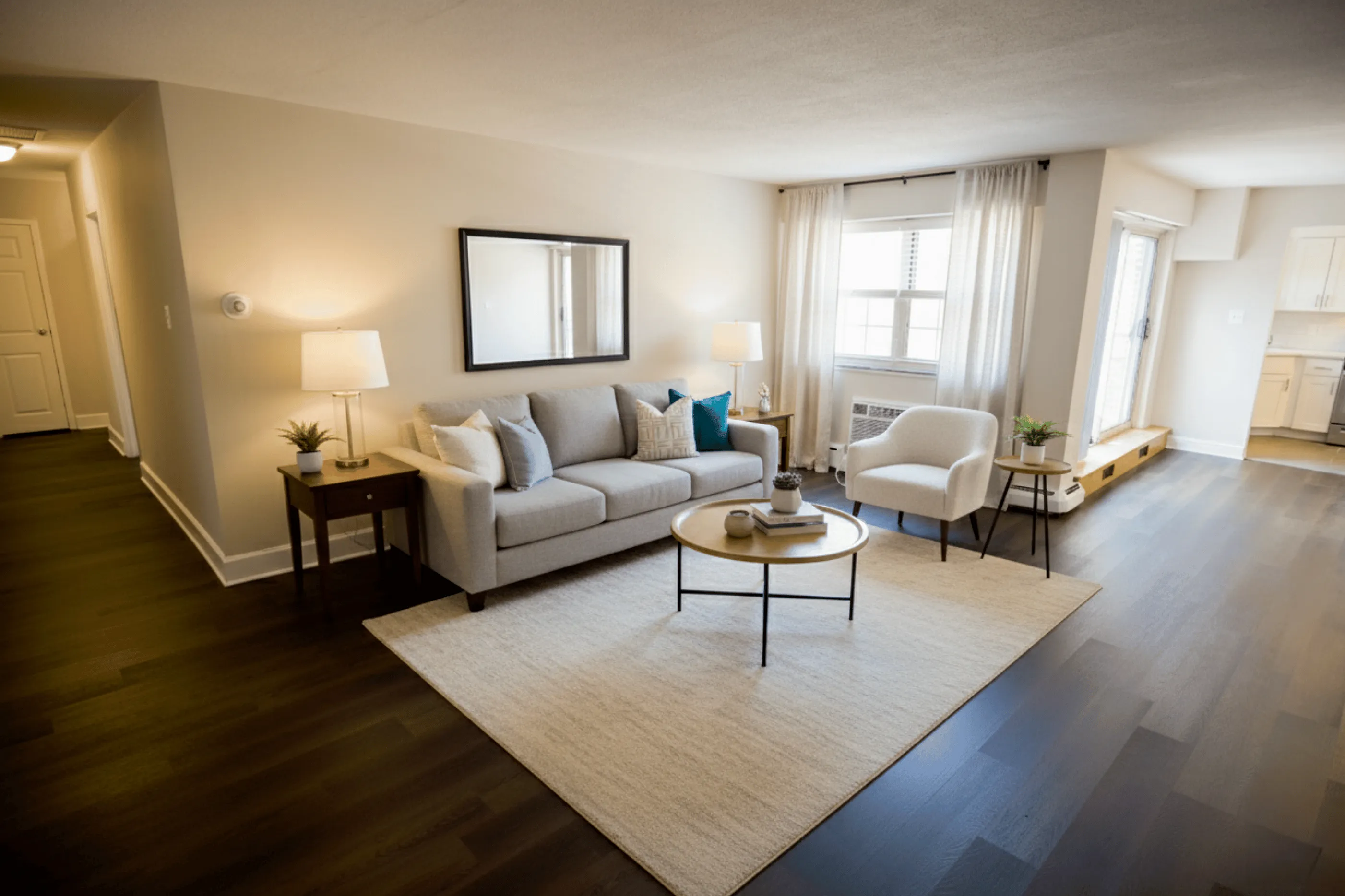 Inviting living room with elegant sofa, modern armchair, and coffee table, highlighted by warm lighting and hardwood floors.