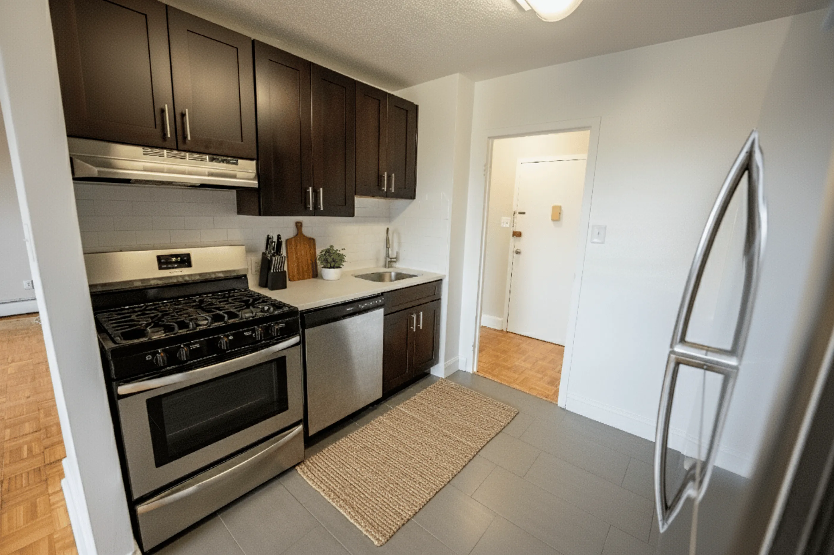 Modern kitchen with sleek stainless steel appliances, dark wood cabinetry, and contemporary tile flooring, creating a stylish and functional cooking space.