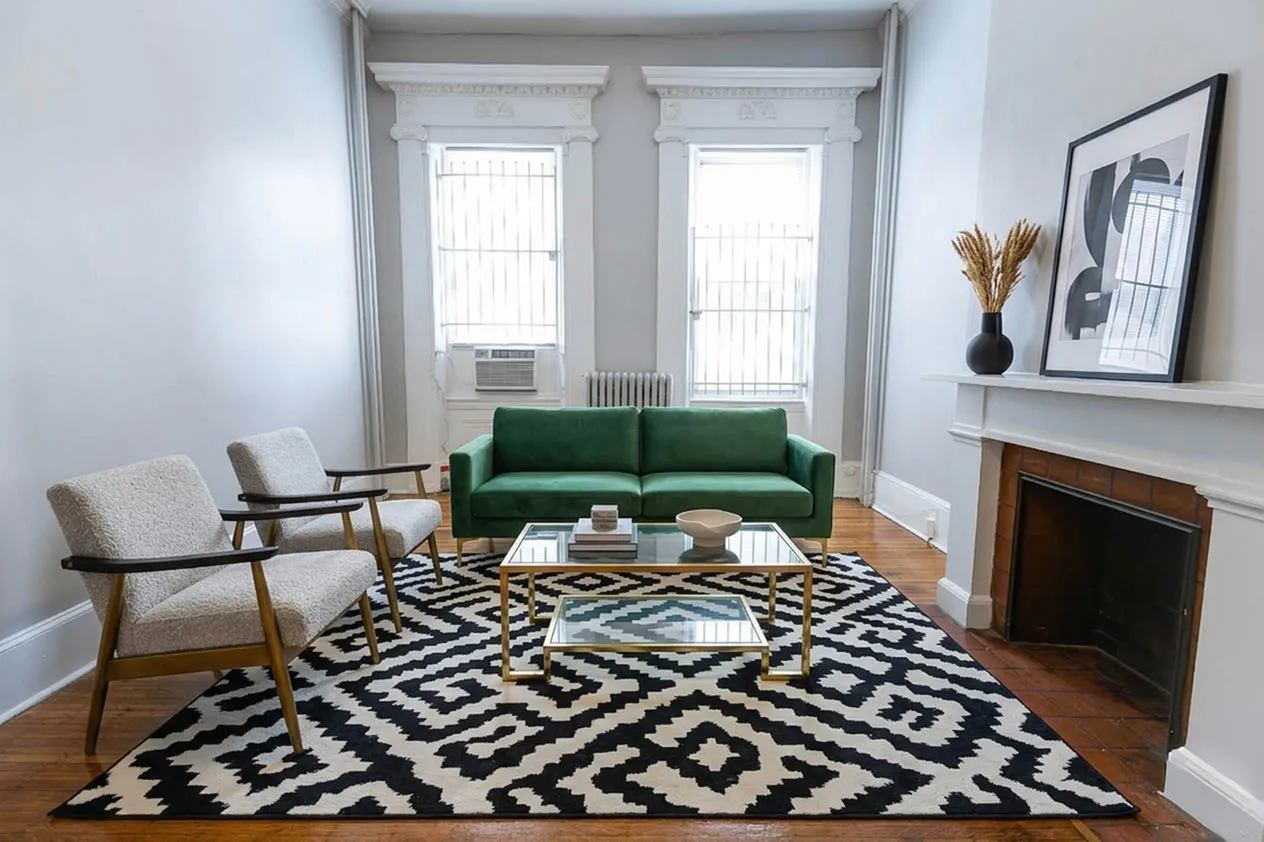 Chic living room featuring a stylish green sofa, modern armchairs, and a bold patterned rug, creating a cozy and inviting space.