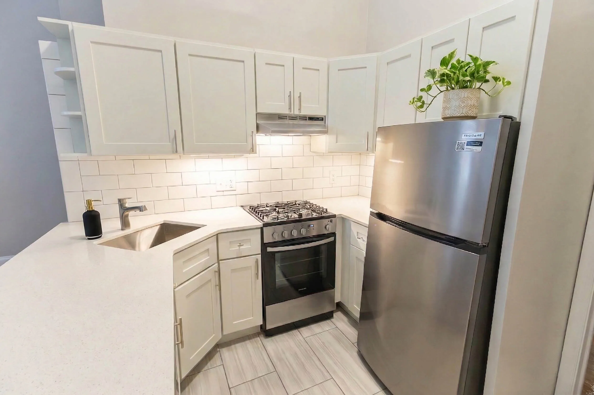 Modern kitchen with sleek stainless steel appliances, white cabinetry, and elegant tile backsplash, perfect for culinary enthusiasts.