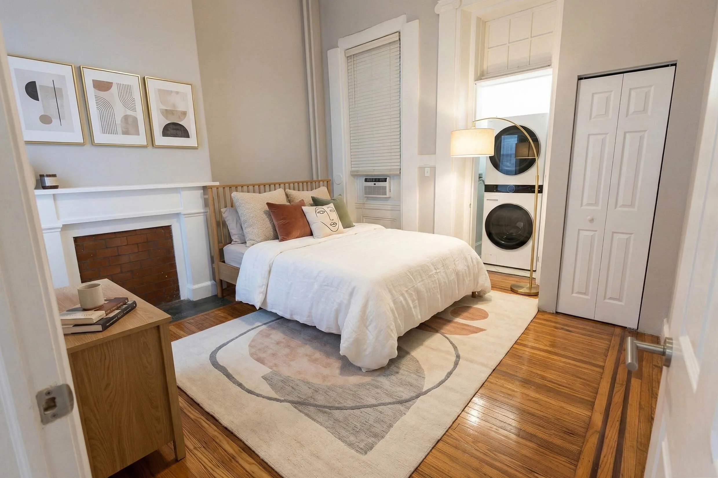 Charming bedroom with elegant wooden floors, cozy bed, modern artwork, and convenient in-unit laundry.