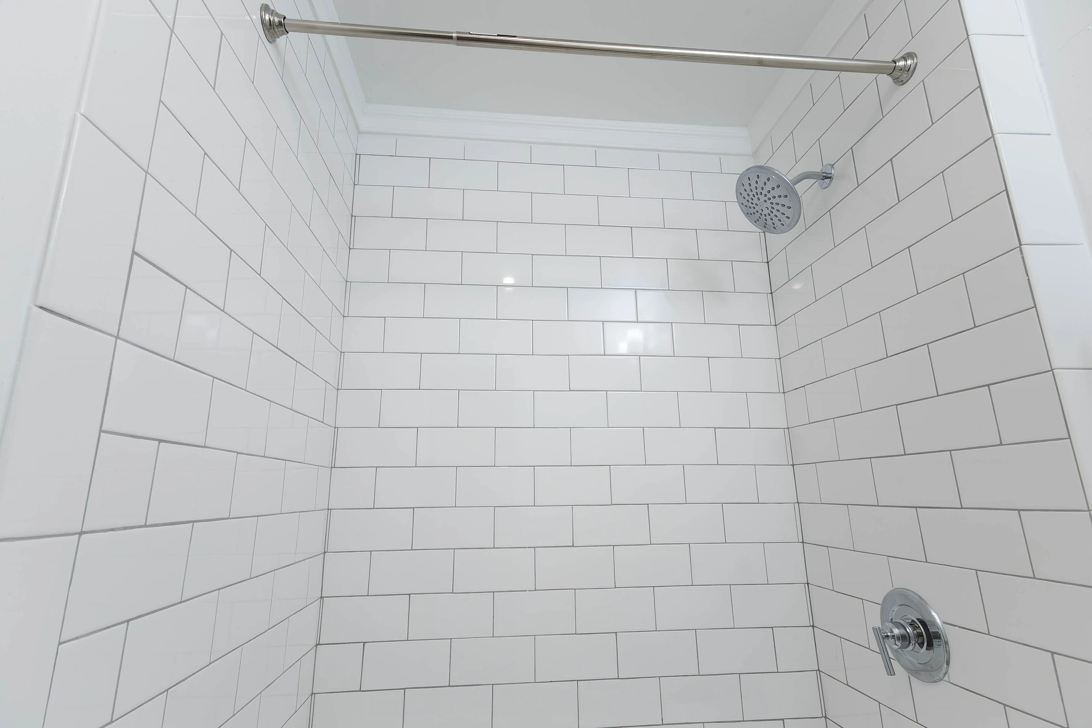 Modern bathroom with sleek white subway tiles and a chrome showerhead, offering a clean and elegant design.