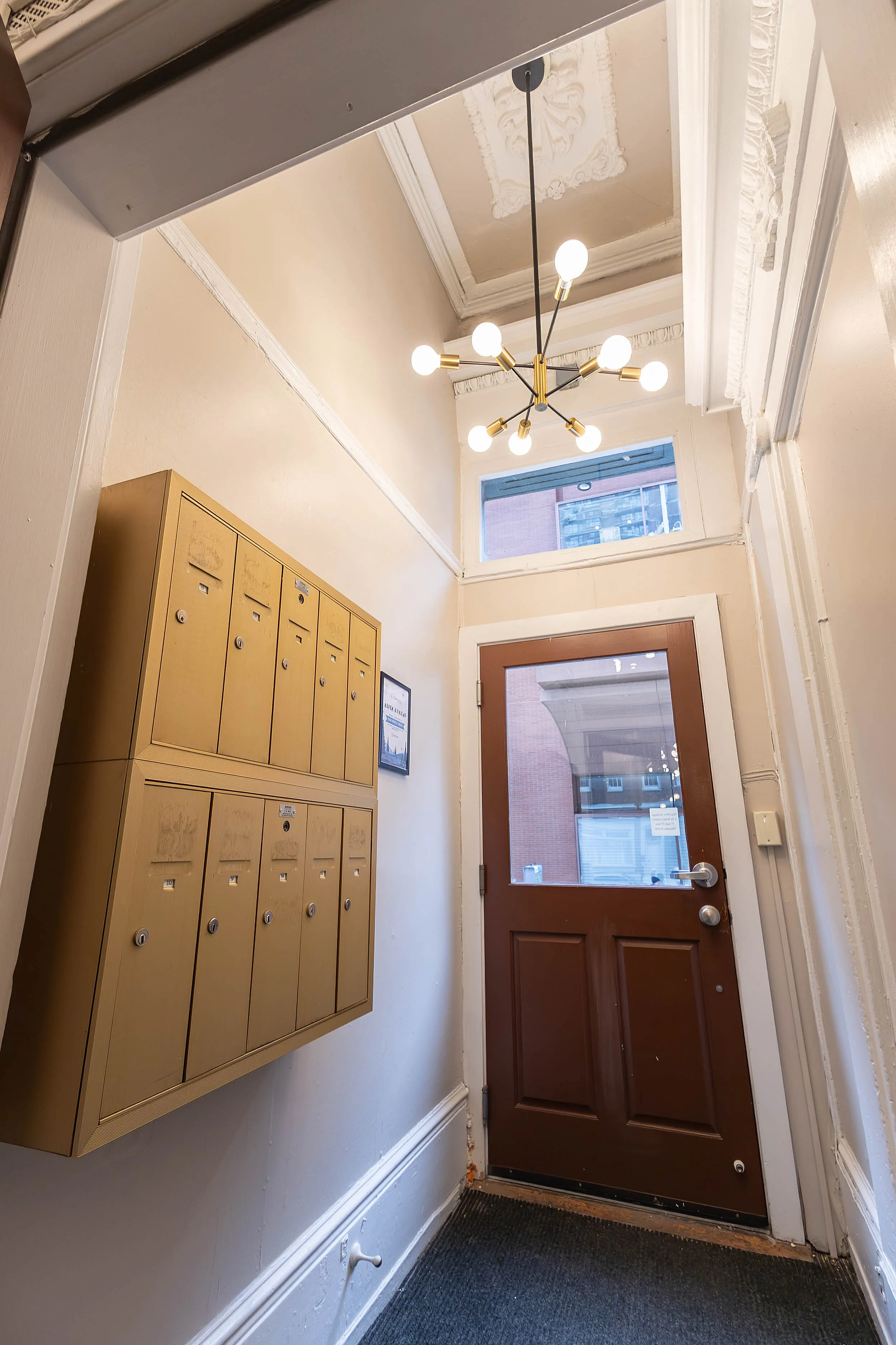 Charming foyer entrance featuring elegant molding, modern chandelier, and well-organized mailbox area.