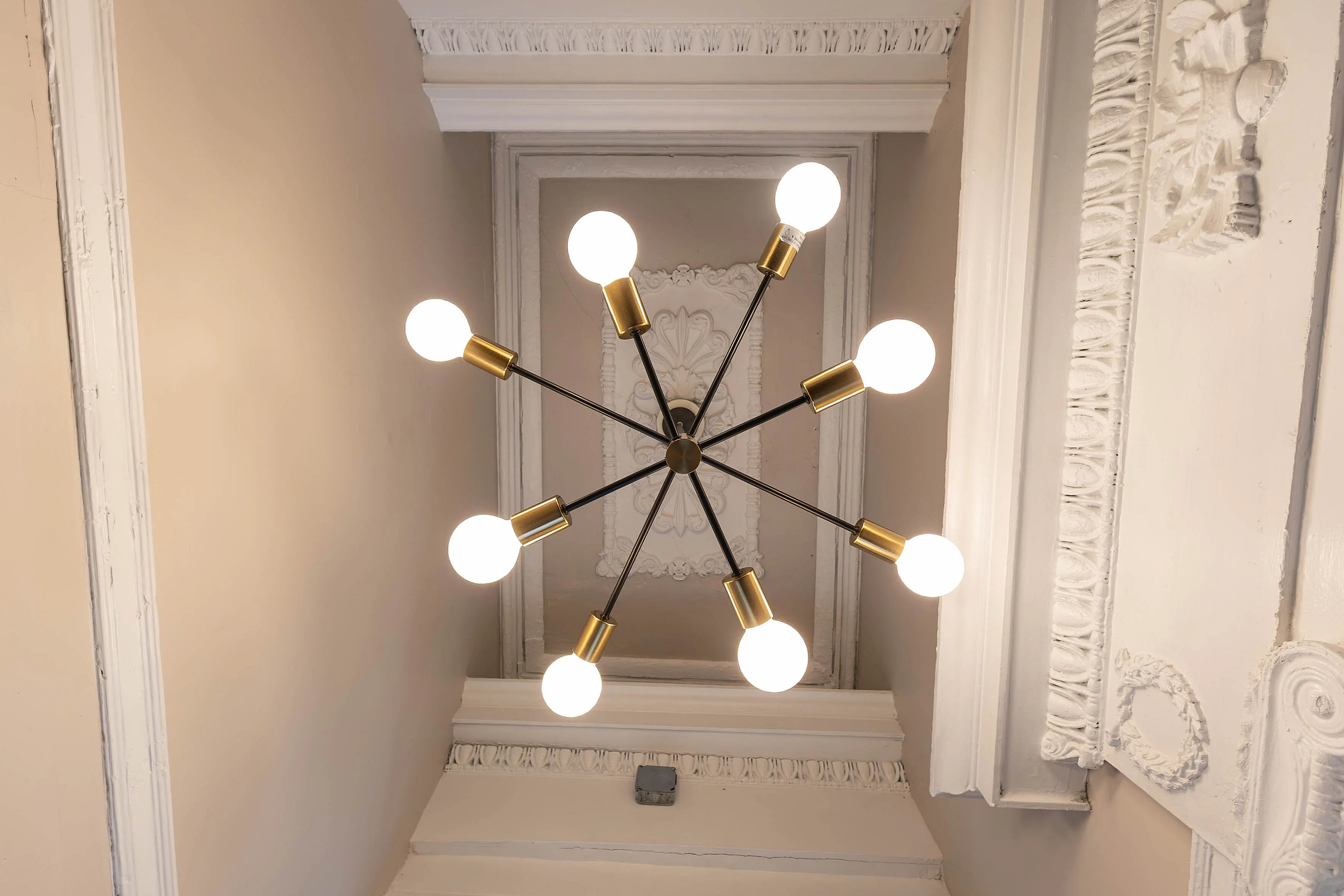 Elegant ceiling with a modern, sputnik-style chandelier and intricate crown molding details.