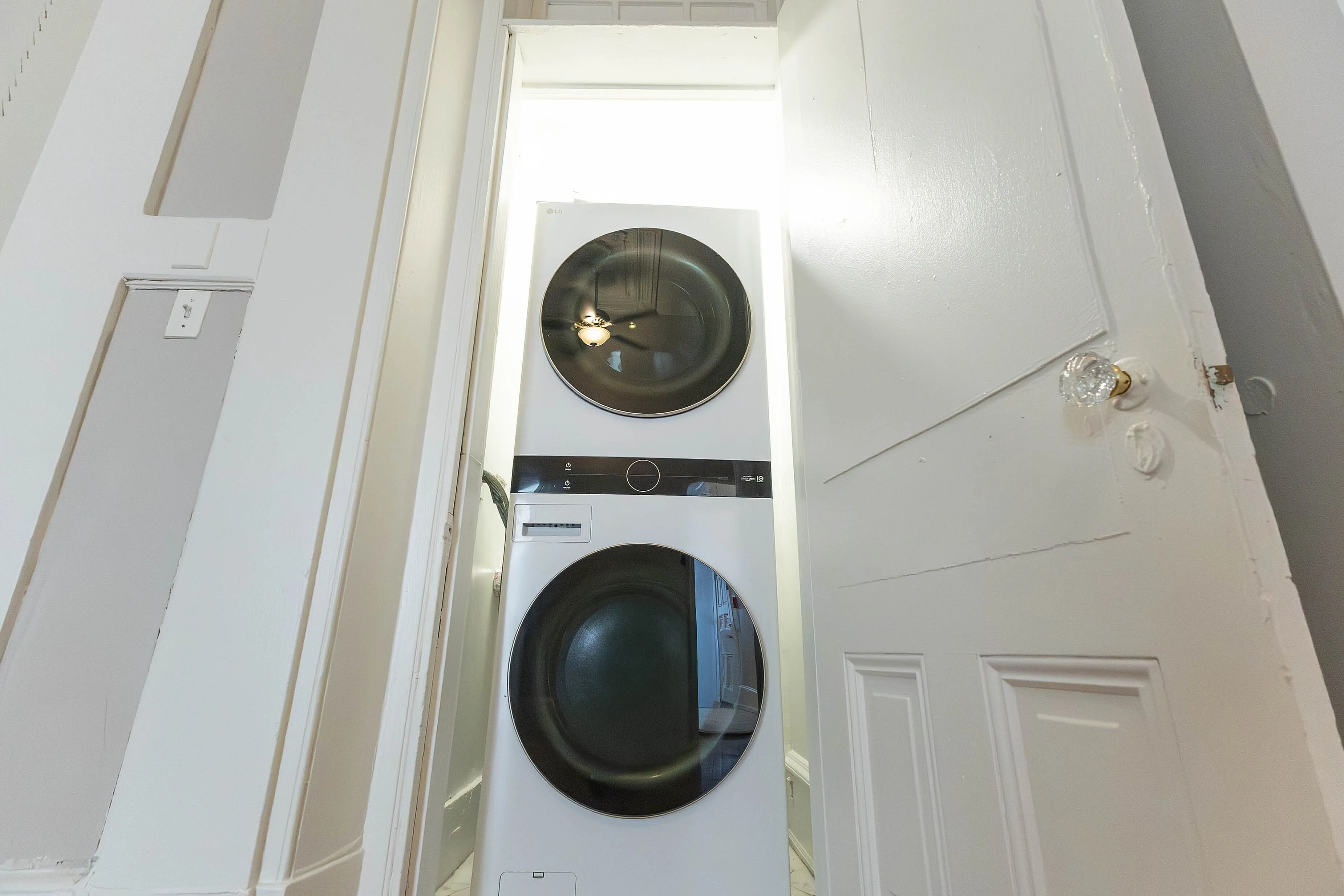 Modern stacked washer and dryer elegantly tucked in a closet with white doors, offering stylish convenience.