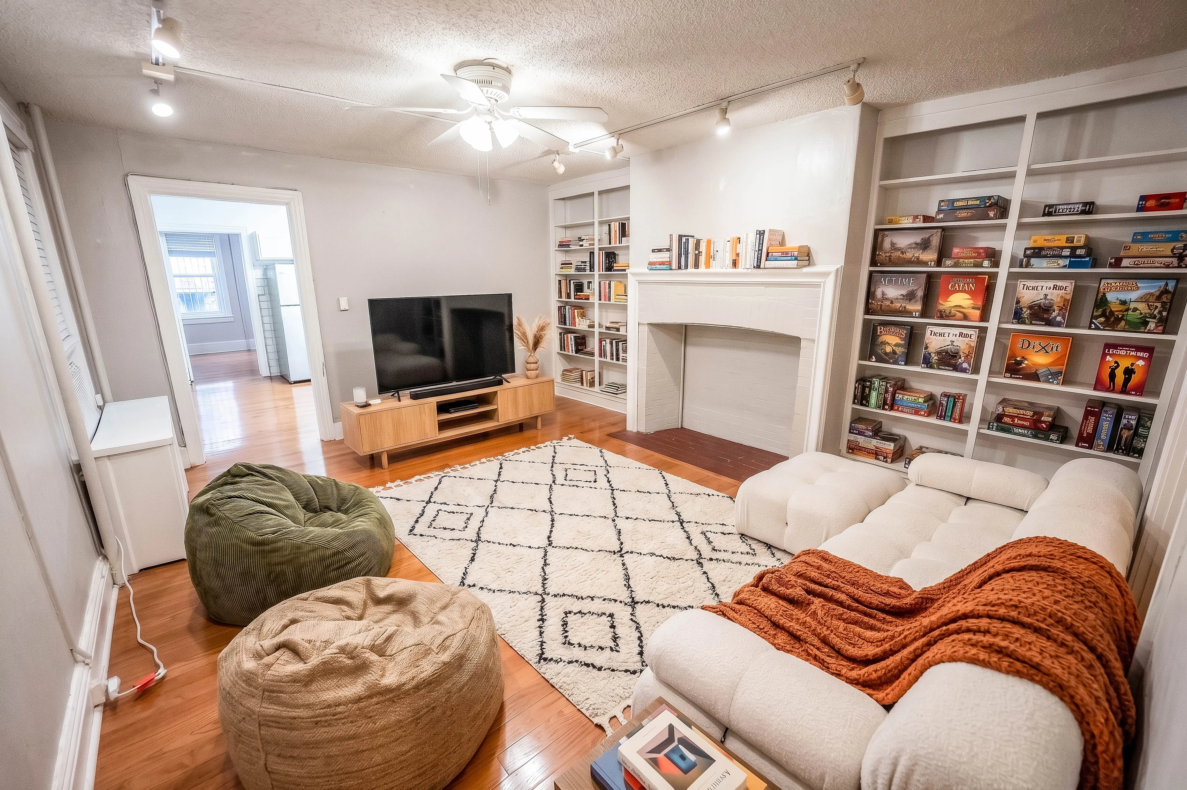 Cozy living room featuring plush seating, a modern entertainment center, and elegant built-in bookshelves filled with books and games.