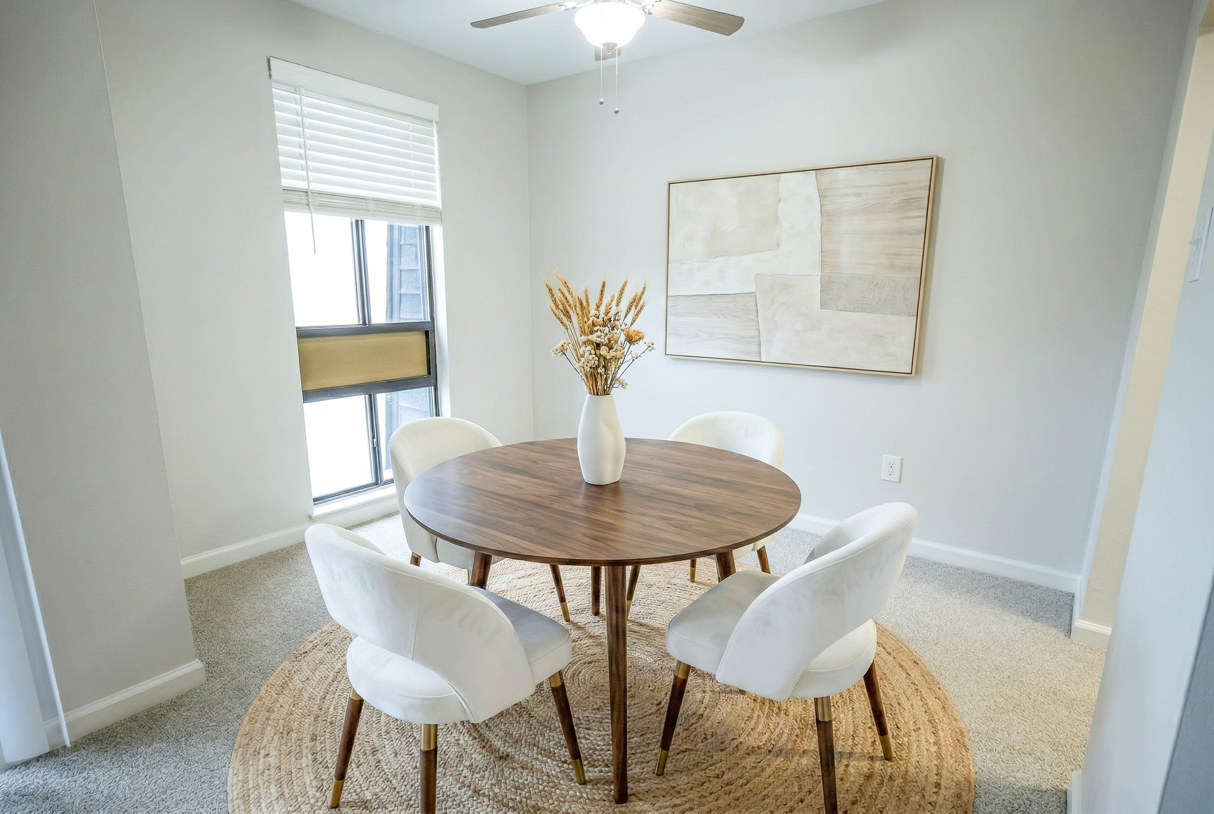 Charming dining area with a round wooden table, elegant white chairs, and a stylish vase centerpiece, perfect for intimate gatherings.