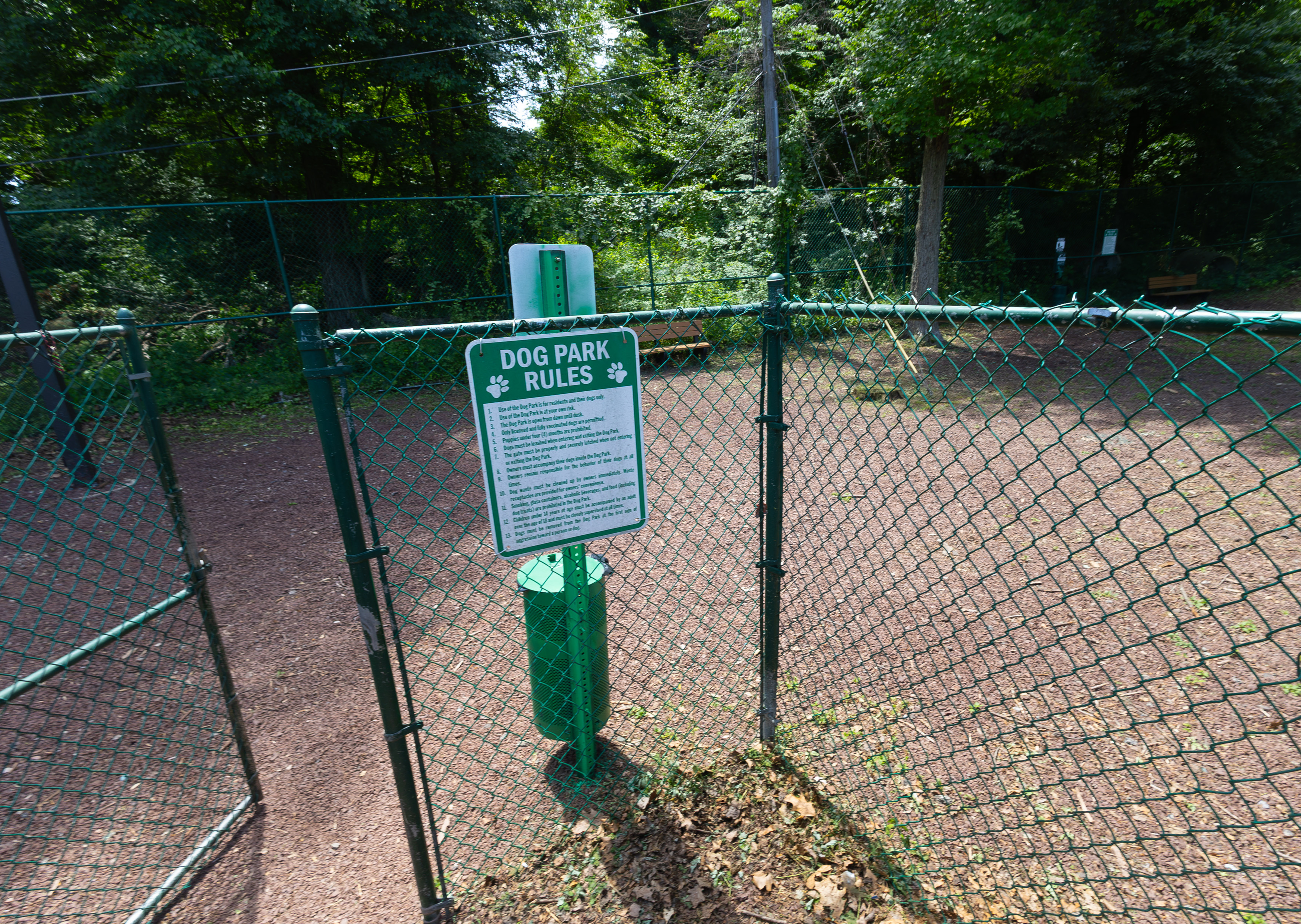 Inviting dog park entry with rule sign and lush greenery, perfect for pet-friendly living.