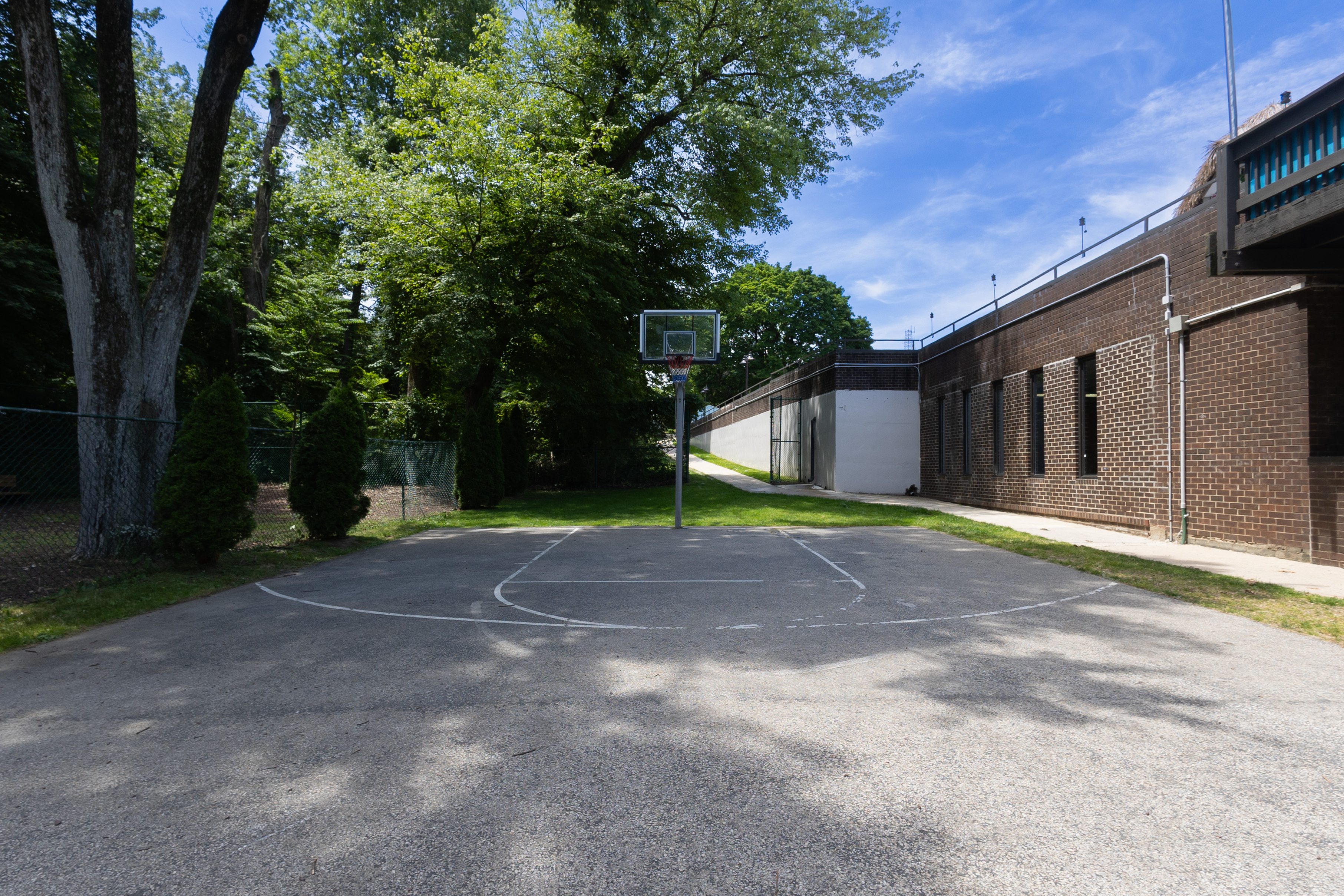 Inviting outdoor basketball court with lush green surroundings and clear blue skies, perfect for recreation and relaxation.