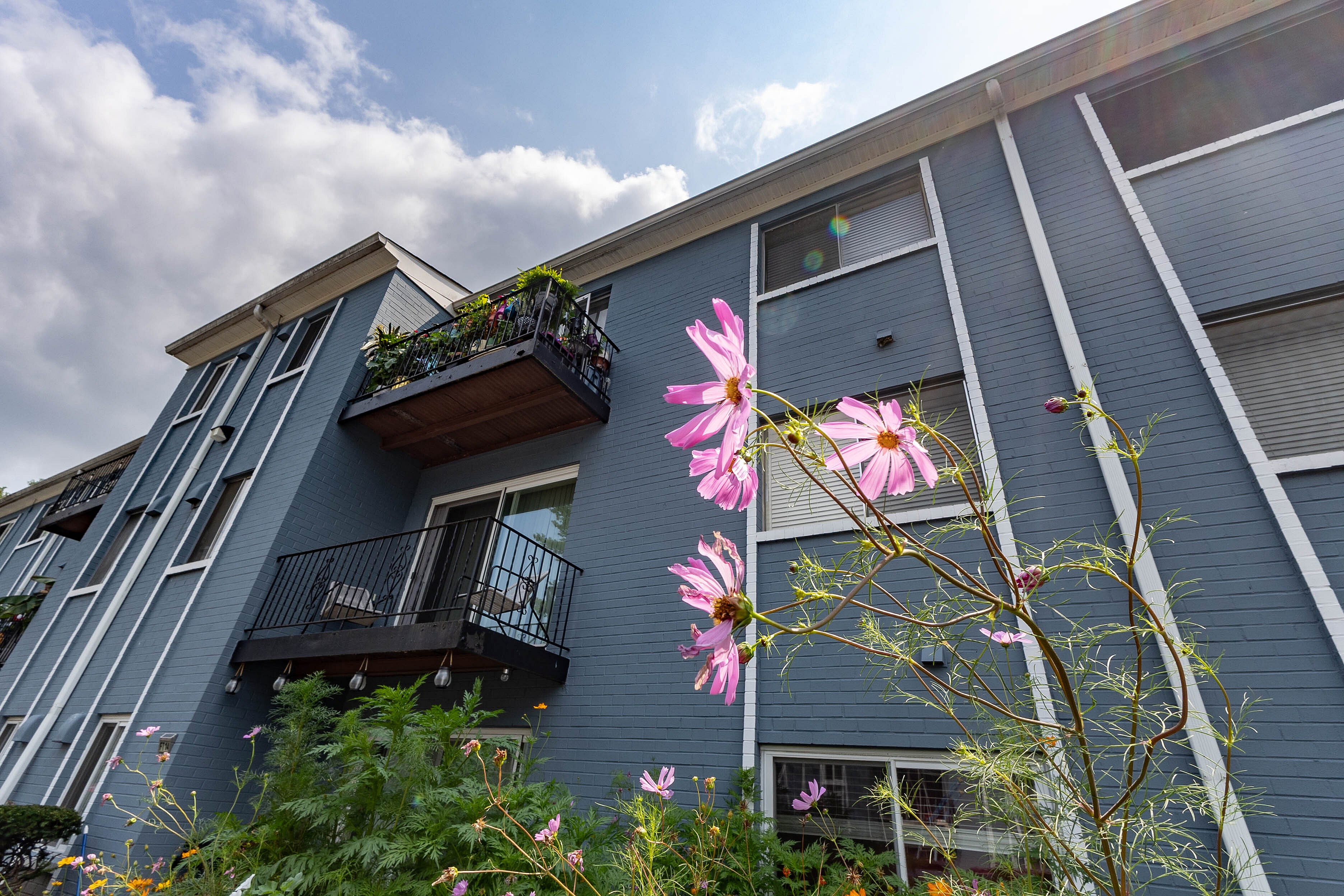 Charming apartment exterior with elegant balconies and vibrant flower garden, showcasing serene and welcoming ambiance.