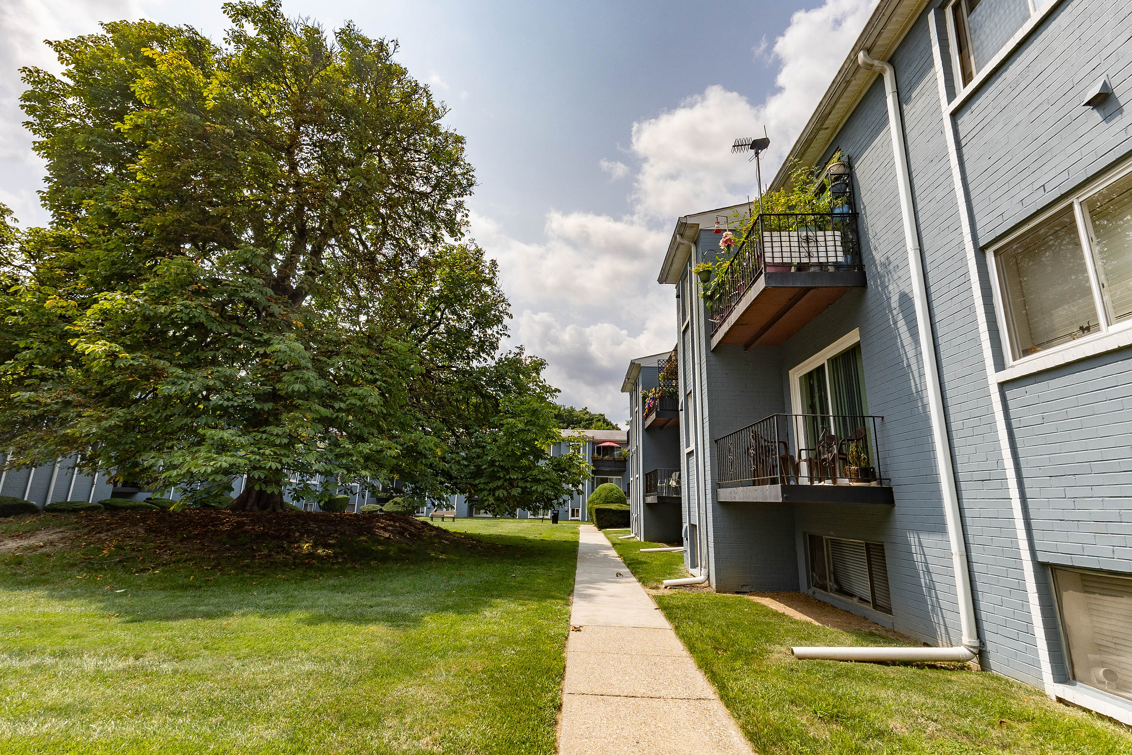 Charming apartment exterior with lush greenery, spacious balconies, and vibrant community ambiance.