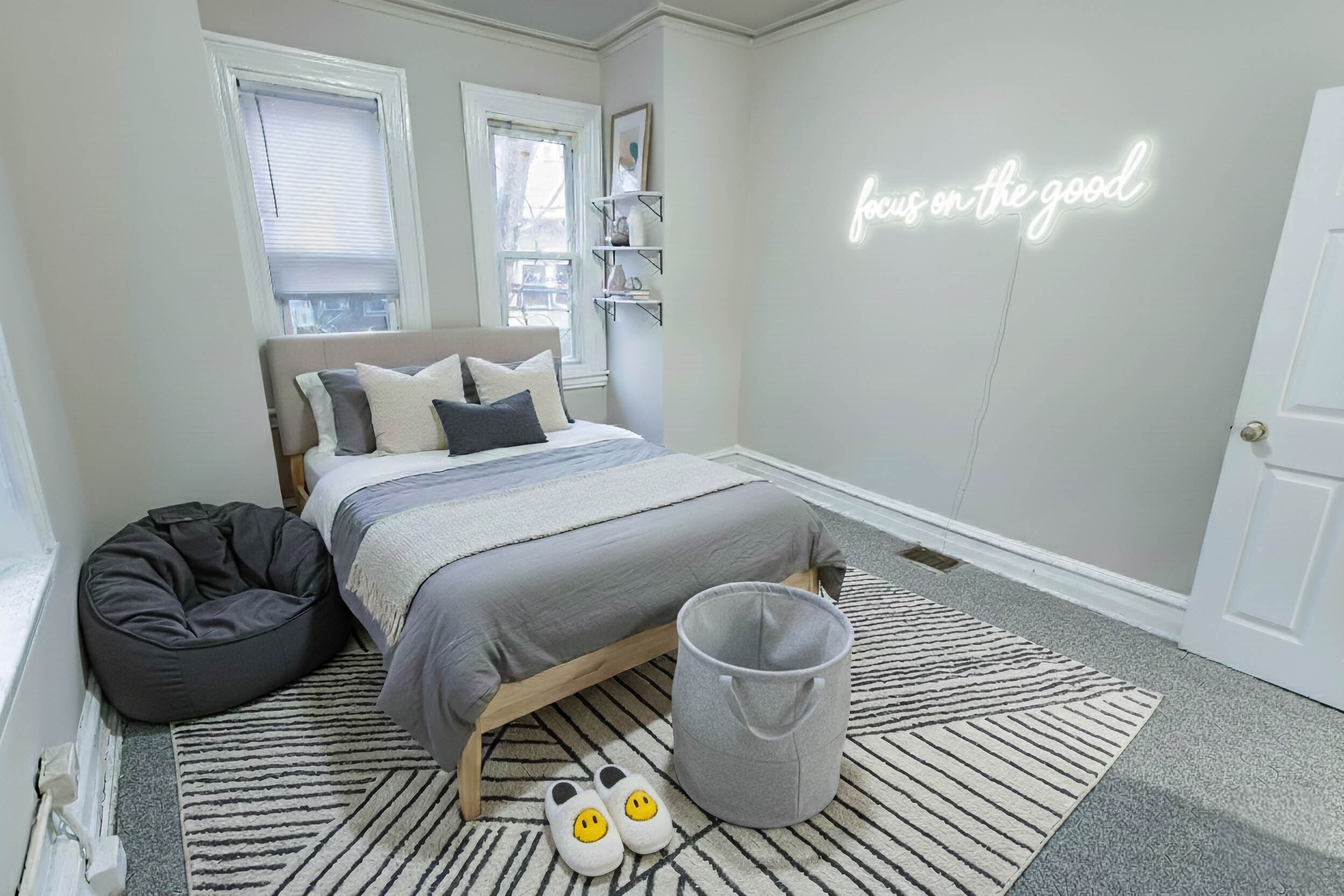 Inviting bedroom with plush bedding, chic neon wall art, and cozy bean bag chair accentuating a serene ambiance.