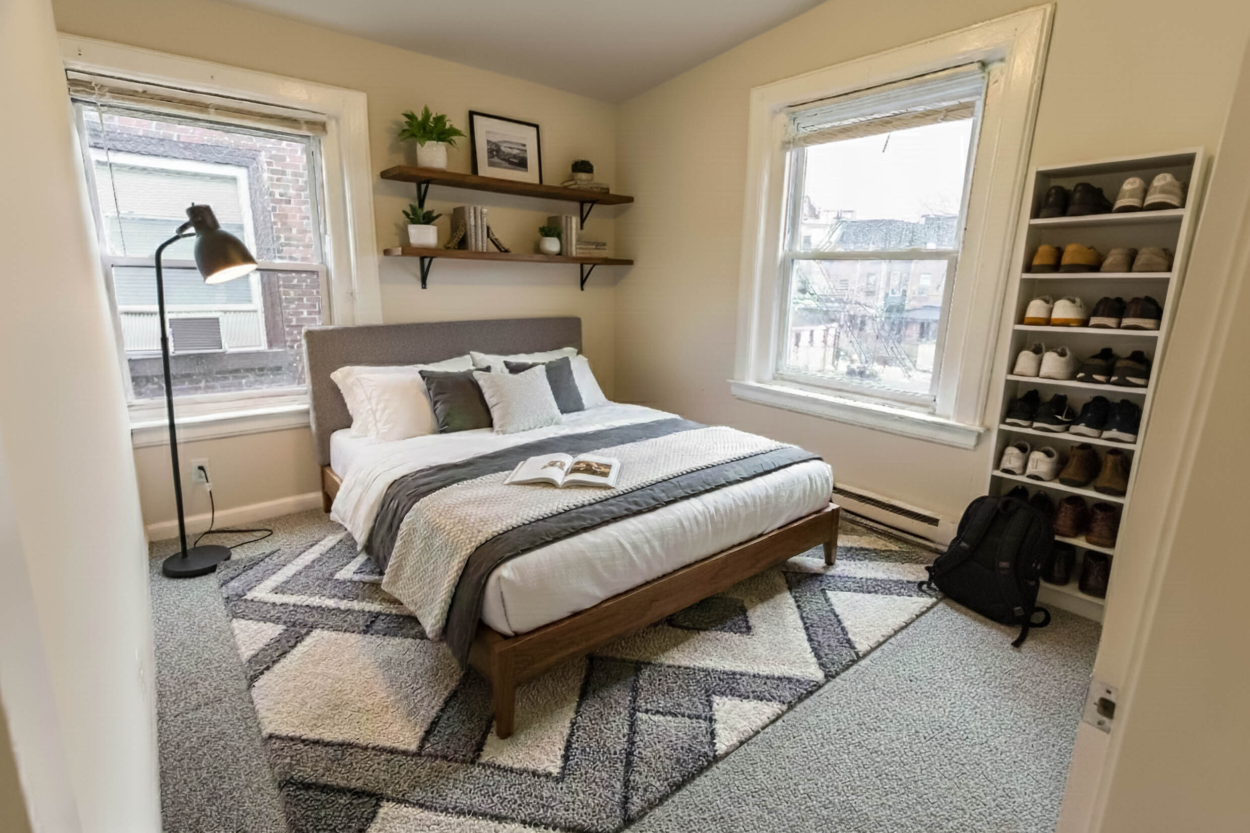 Cozy and stylish bedroom with modern decor, featuring a comfortable bed, elegant shelving, large windows for natural light, and an organized shoe rack.