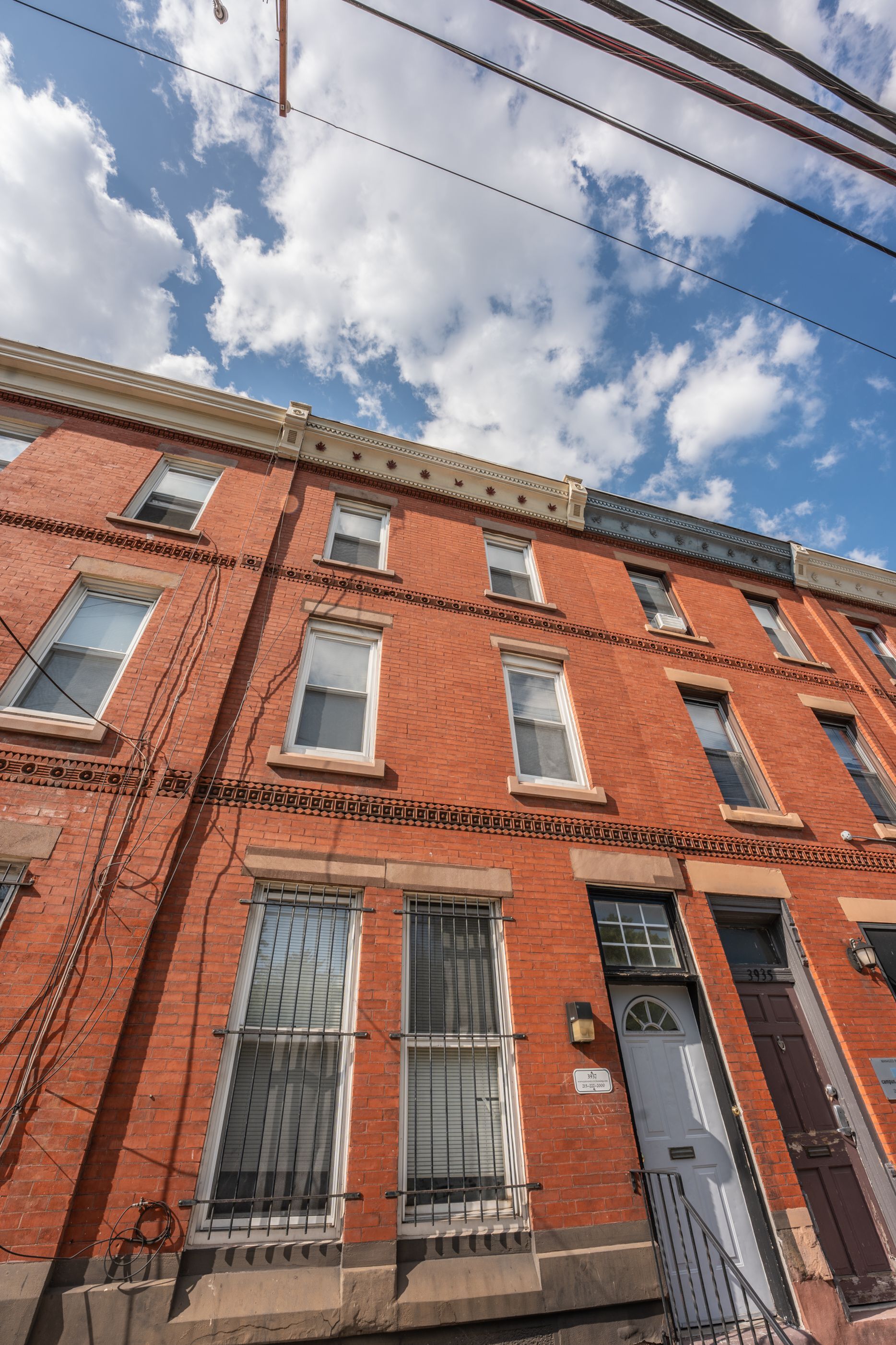 Charming urban red brick townhouse with elegant architecture and large windows under a bright blue sky.