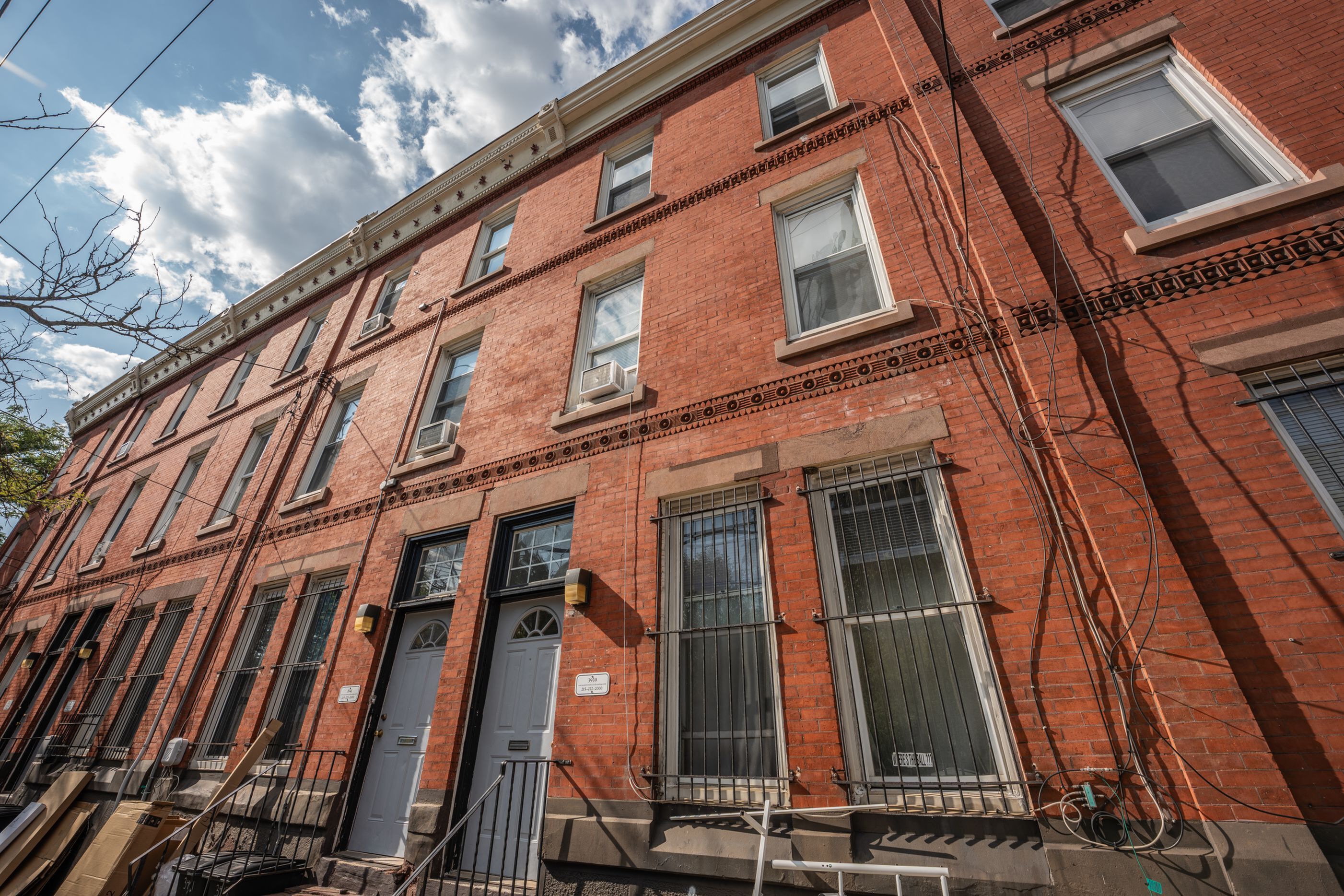 Charming red brick apartment building with classic architectural details, featuring multiple levels and large windows, under a clear sky.
