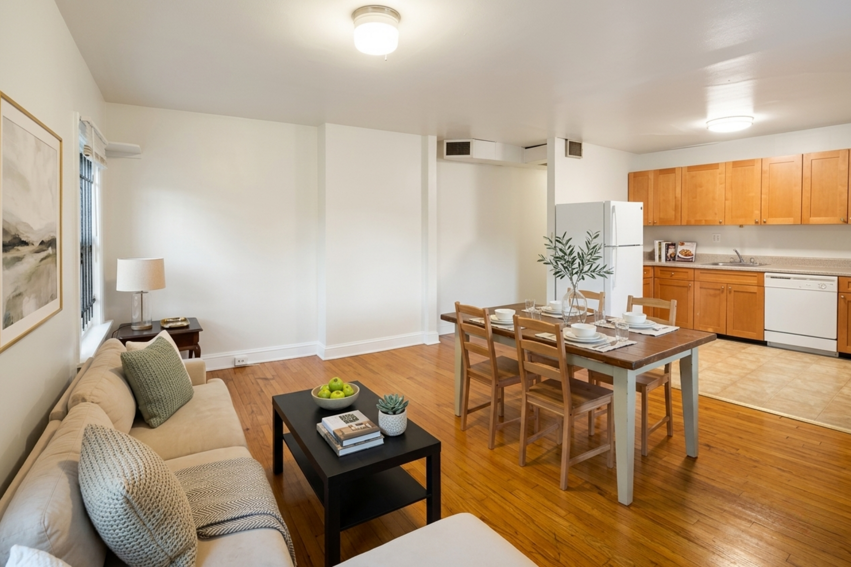 Inviting open-concept apartment with cozy living area, elegant dining space, and modern kitchen featuring wooden cabinetry.