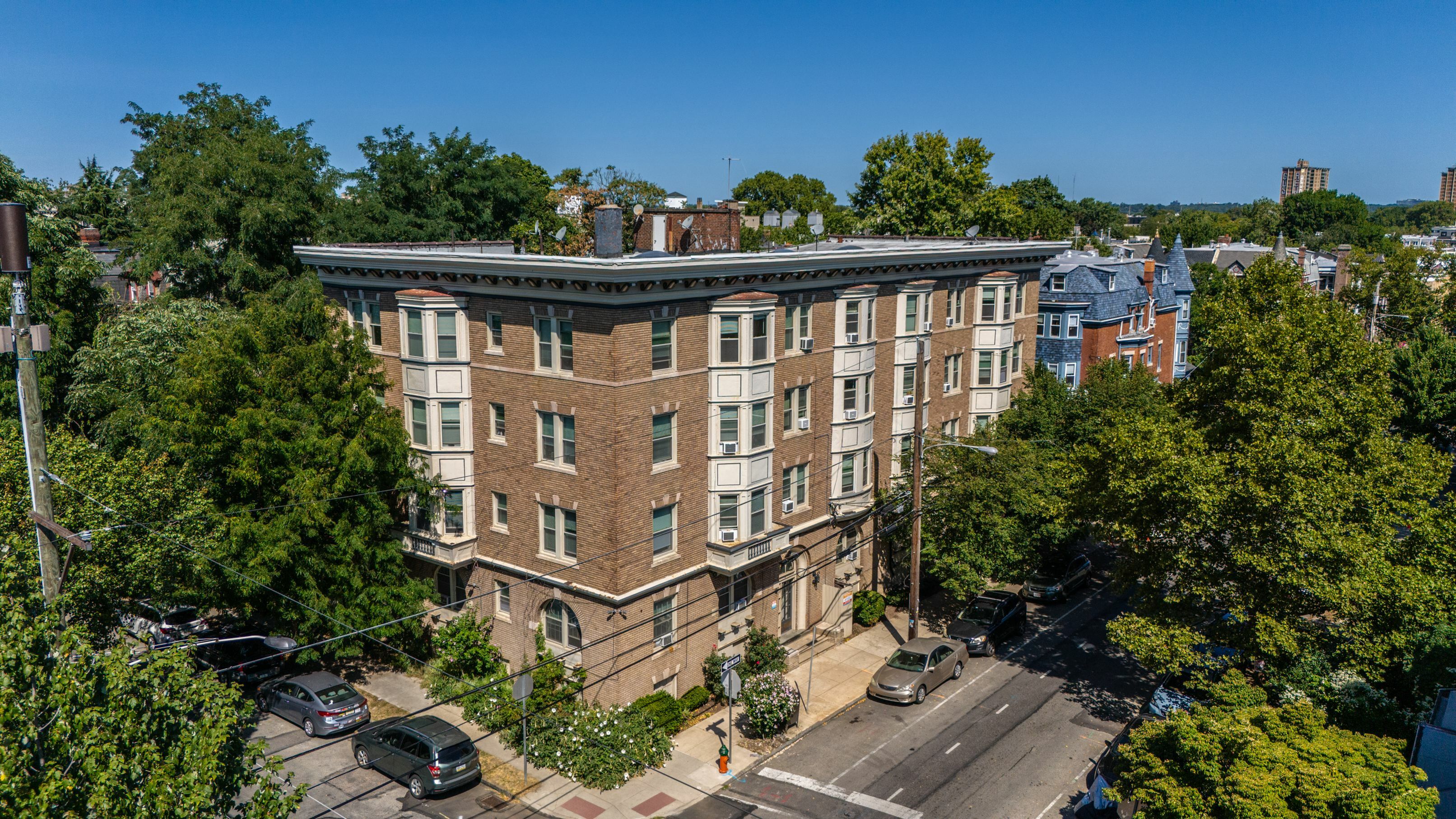 Charming brick apartment building nestled in a tree-lined neighborhood with nearby parking and vibrant surroundings.