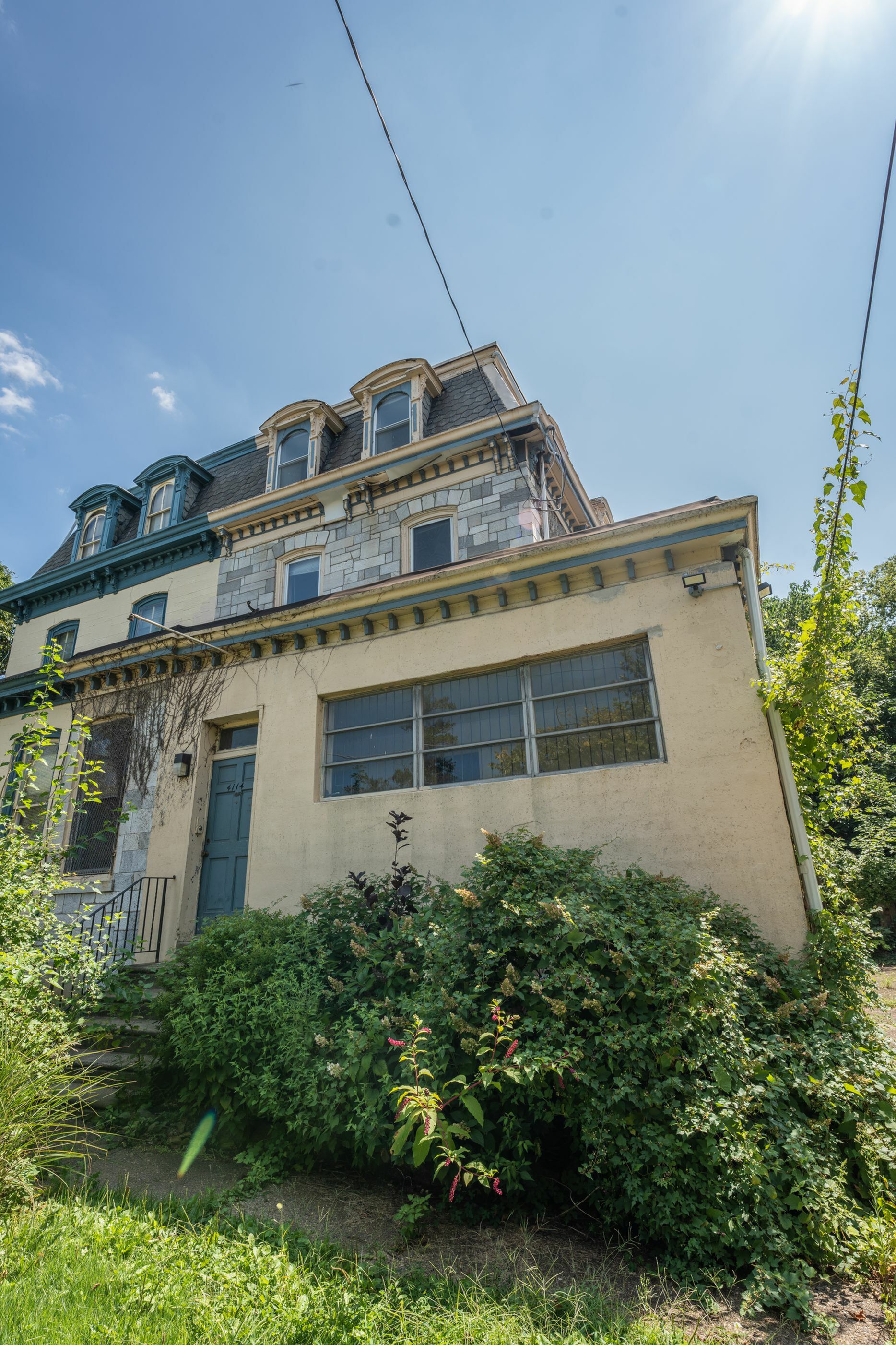 Charming historic townhouse with classic architectural details, featuring dormer windows and a lush front garden.