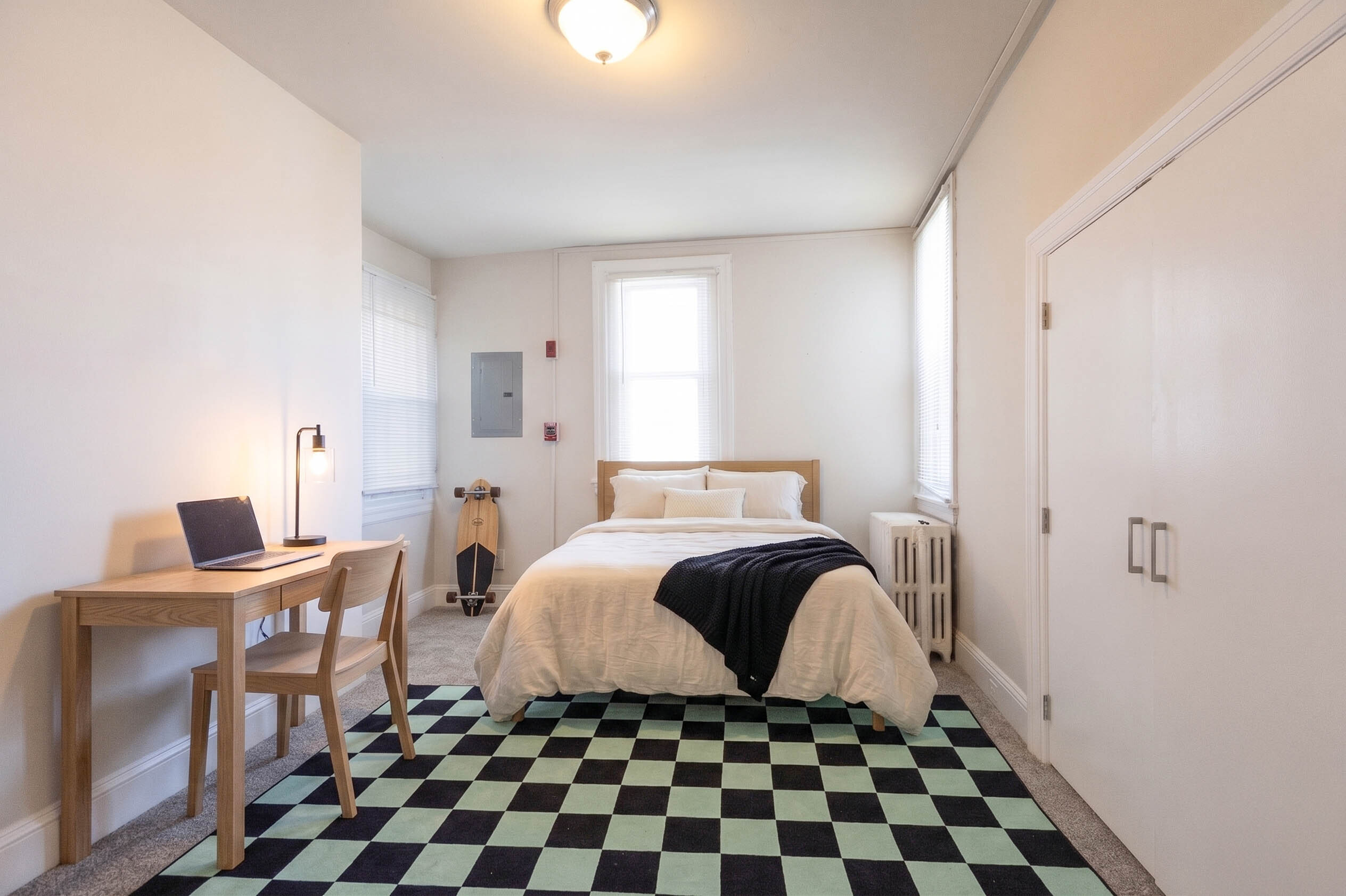 Bright and stylish bedroom featuring a cozy bed, modern desk, and elegant decor, complete with a trendy skateboard accent.