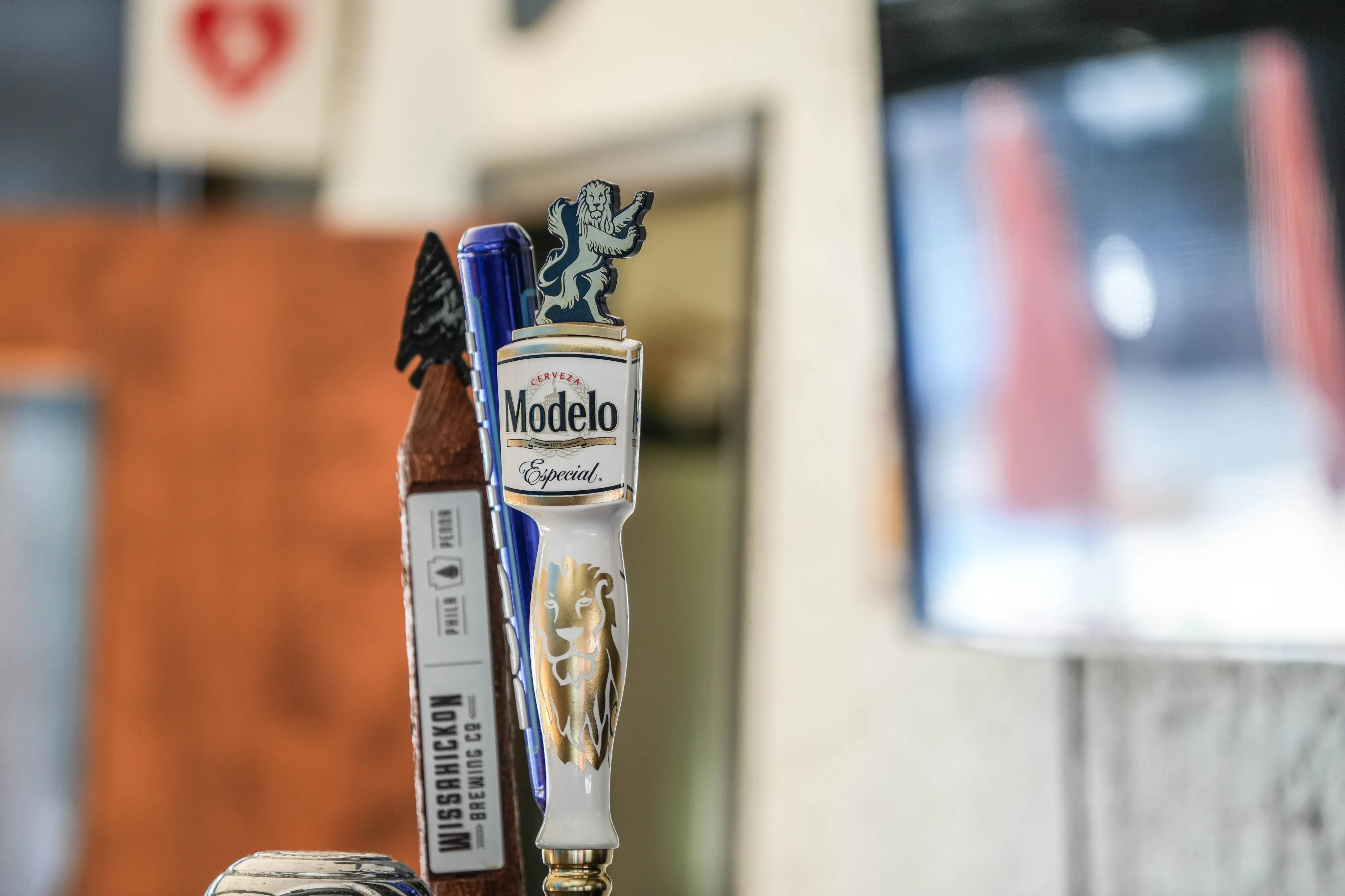Close-up of stylish beer taps featuring a decorative Modelo Especial and a Wissahickon Brewing Co design, set in an inviting bar ambiance.