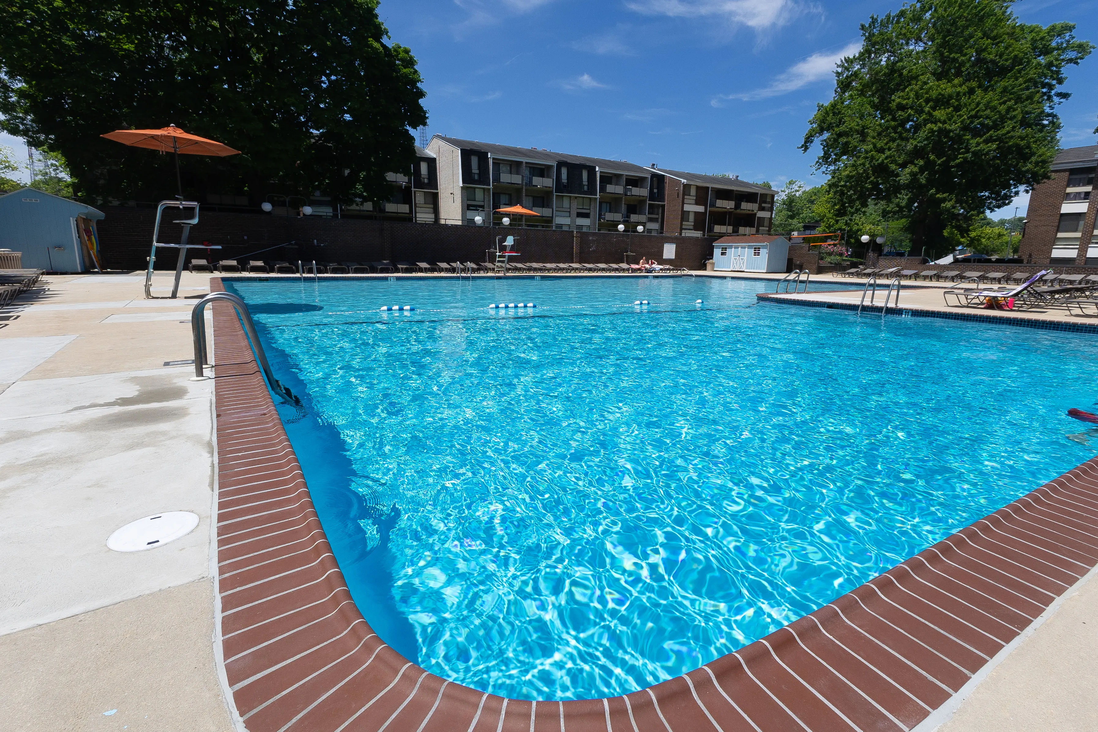Inviting outdoor swimming pool with crystal-clear water, surrounded by sun loungers and shaded seating areas, perfect for relaxation.