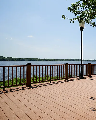 Scenic waterfront deck with elegant benches and classic lampposts under a clear blue sky, perfect for relaxation and enjoying nature.