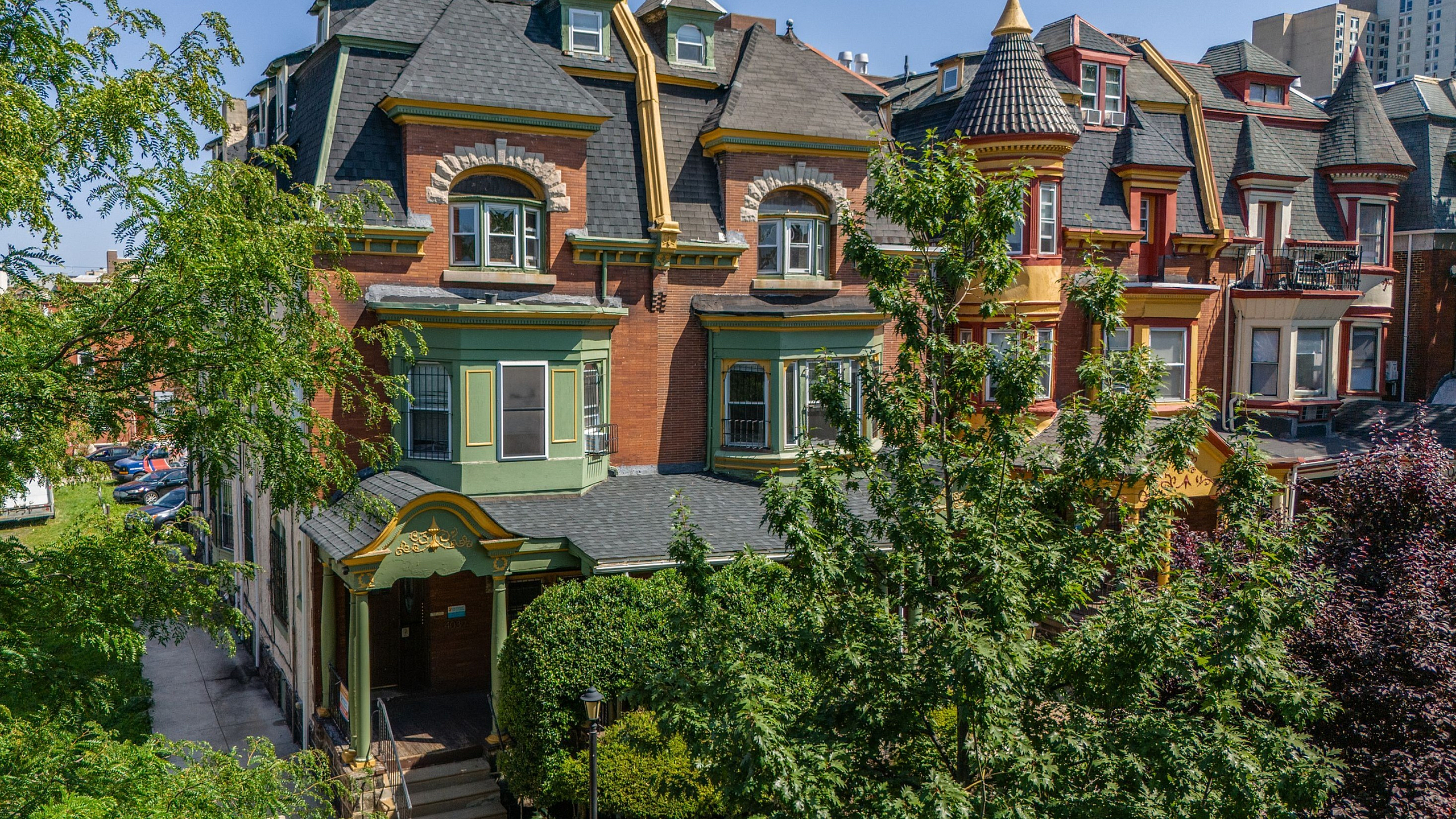 Charming Victorian-style brick apartment building with lush greenery and elegant architectural details, set in a vibrant urban neighborhood.