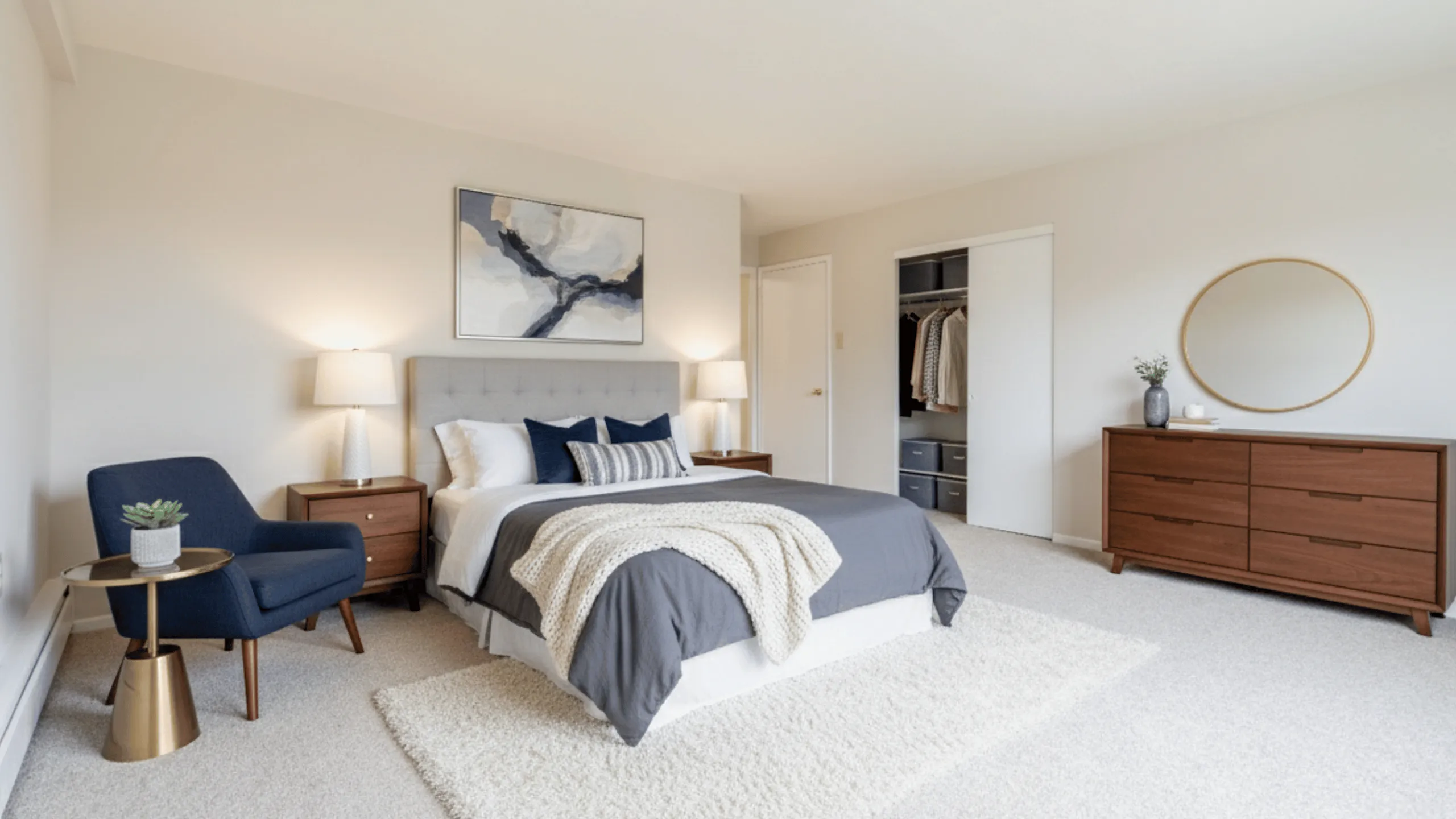 Elegant bedroom with stylish decor, featuring a cozy bed with soft gray bedding, a modern blue chair, and a chic wooden dresser.
