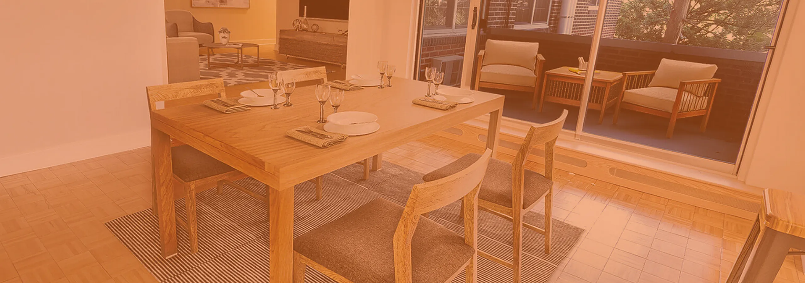 Inviting open-plan dining area with chic wood furniture and elegant table settings, connected to a cozy living room and bright balcony through large glass doors.