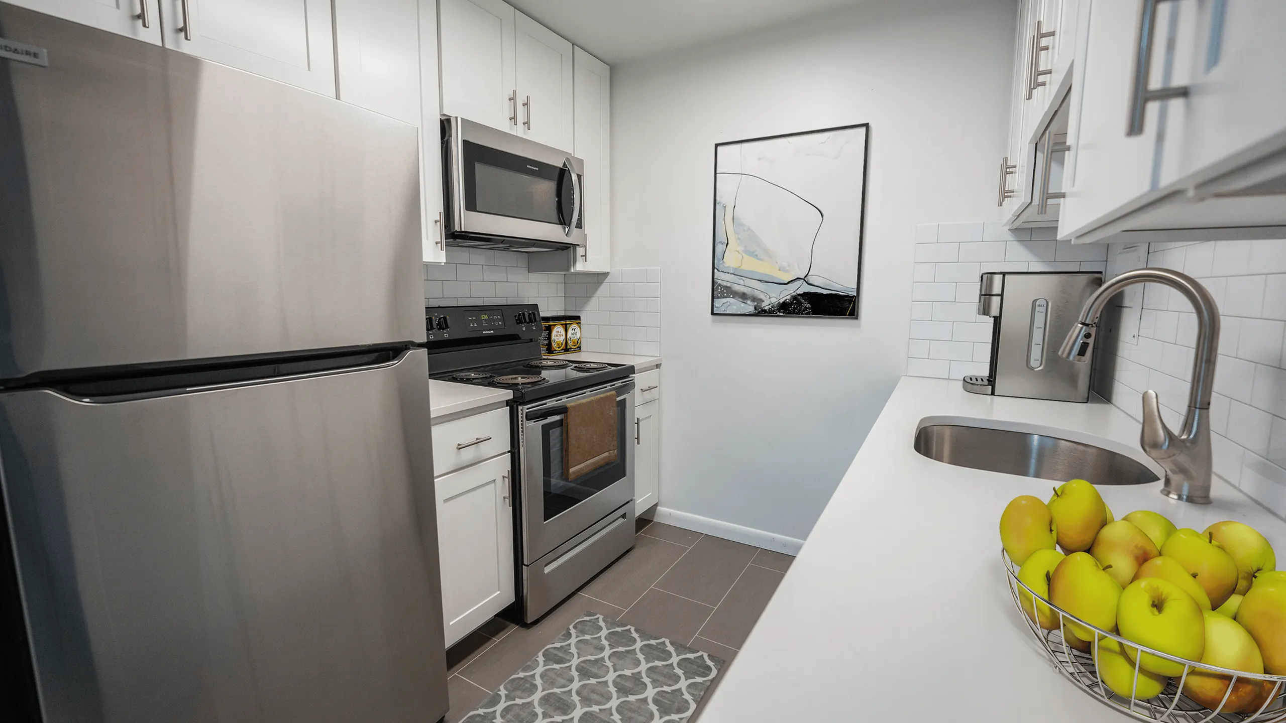 Contemporary kitchen featuring stainless steel appliances, chic white cabinetry, and elegant subway tile backsplash.