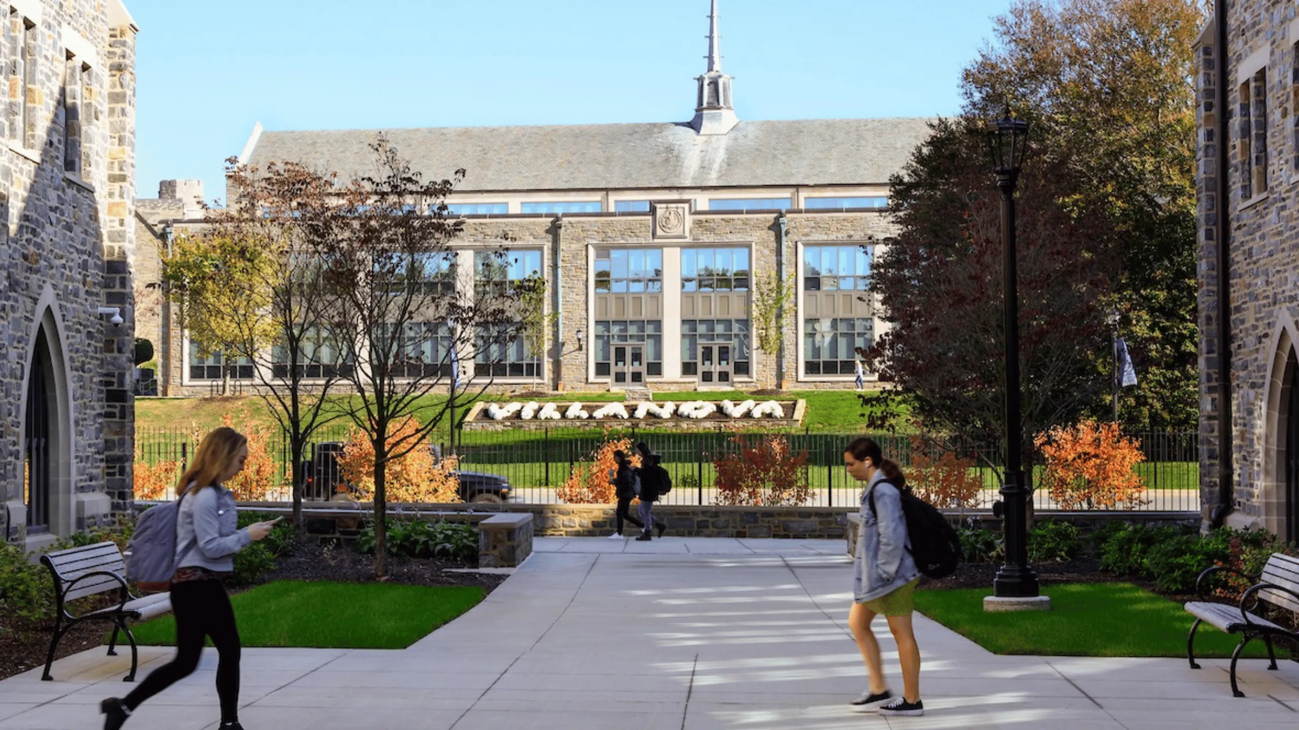 Charming university campus scene with stone architecture, lush greenery, and students walking, highlighting a vibrant academic atmosphere.