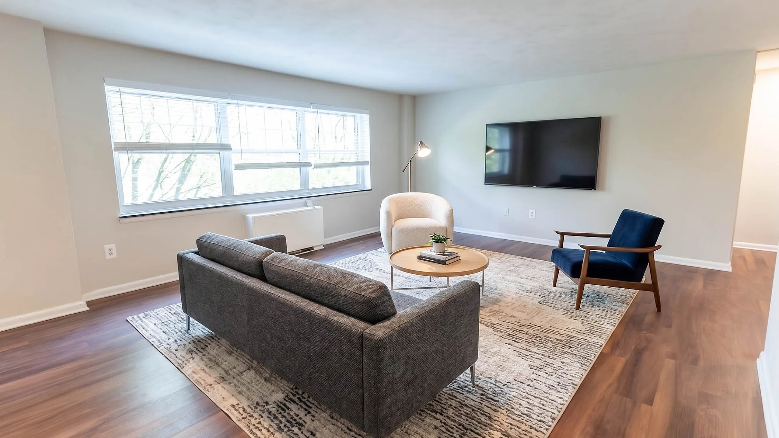 Modern living room with large windows, stylish furniture, and a sleek wall-mounted TV, promising a bright and inviting atmosphere.