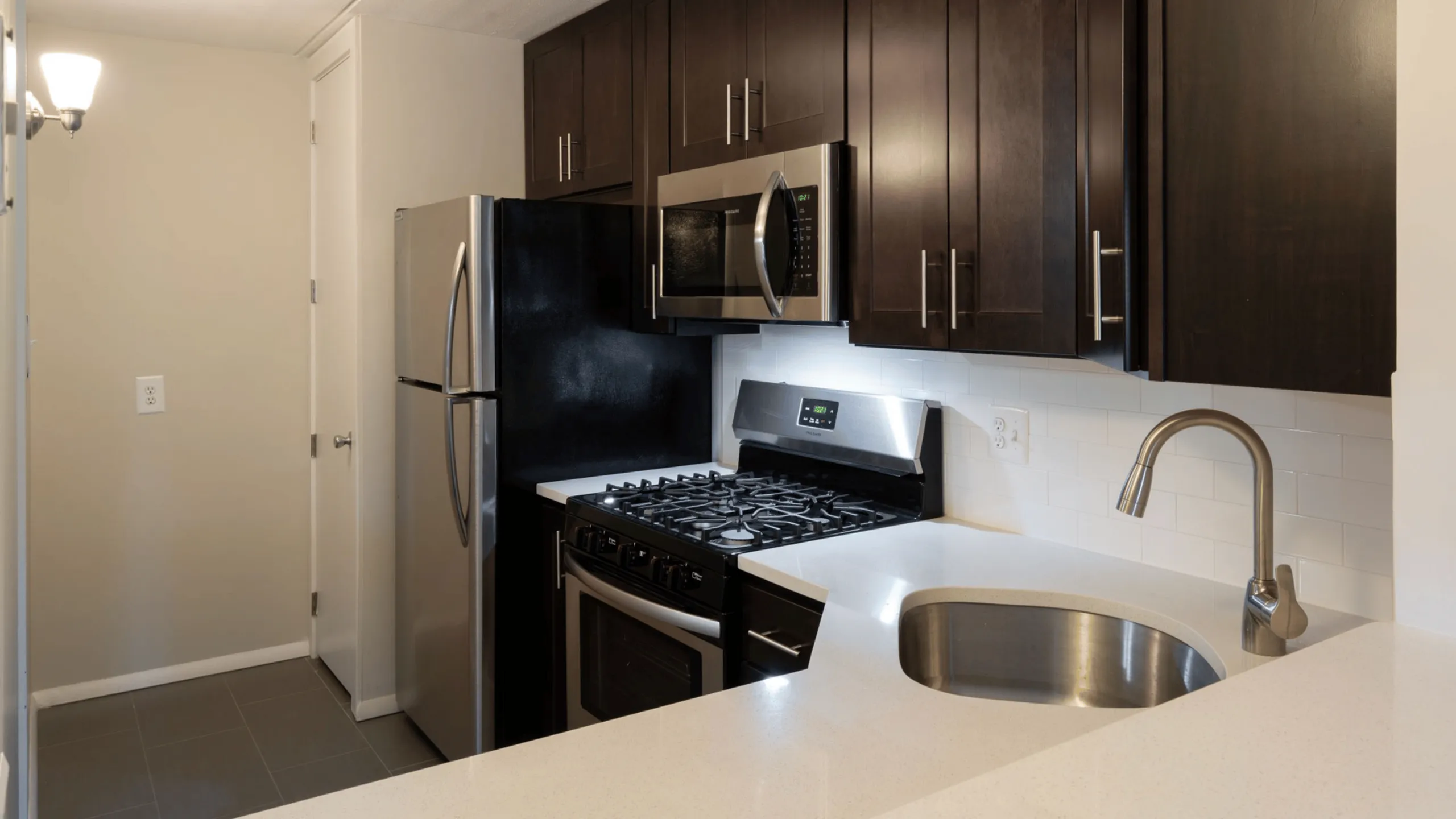 Modern kitchen with sleek dark wood cabinets, stainless steel appliances, and a stylish curved countertop.