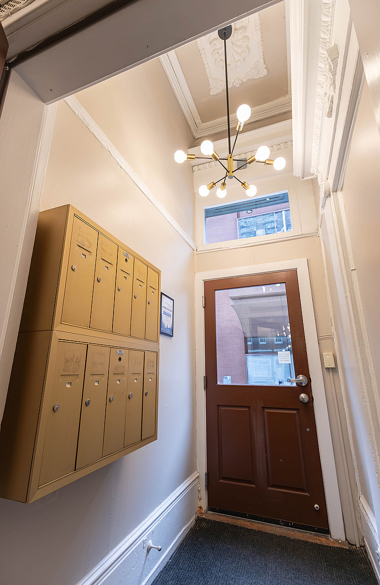 Charming apartment entrance with elegant ceiling design, modern chandelier, and vintage-style mailboxes.