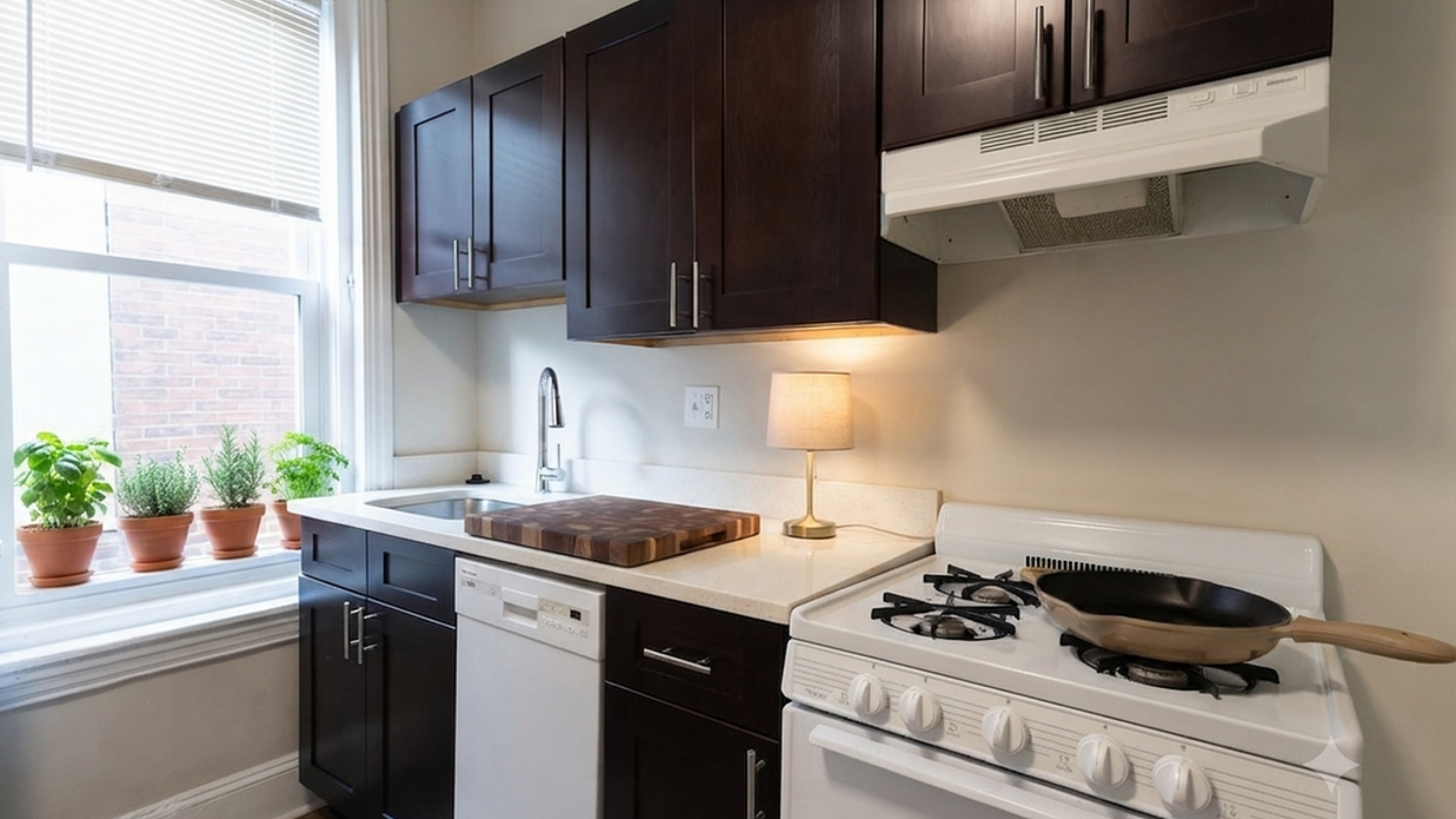 Charming kitchen with modern dark wood cabinetry, cozy lighting, and a window sill adorned with potted plants.