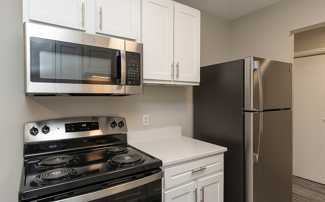 Modern kitchen with sleek stainless steel appliances, including a spacious refrigerator and built-in microwave, set against elegant white cabinetry and polished countertops.