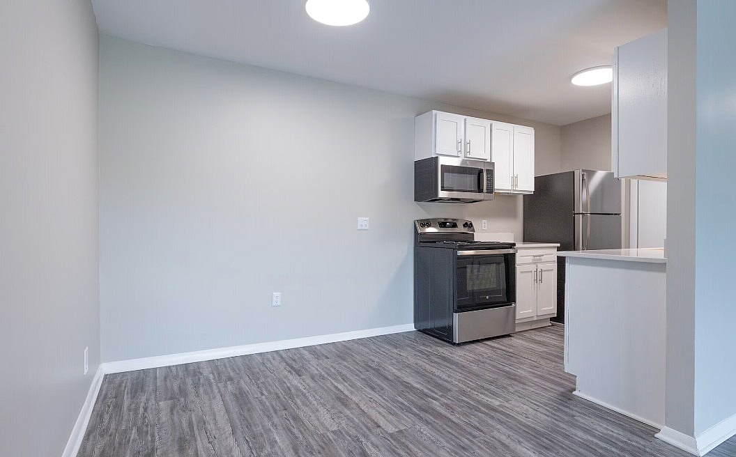 Modern kitchen with stainless steel appliances, sleek cabinetry, and stylish dark wood flooring in an open-concept layout.