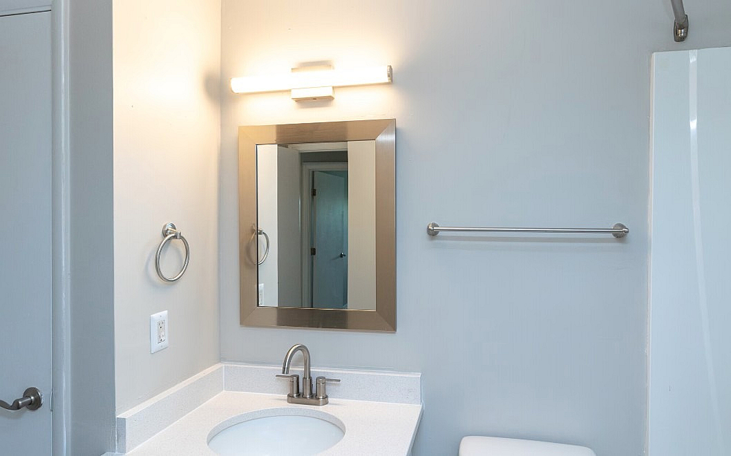 Modern bathroom with sleek design featuring a well-lit mirror, stylish sink, and contemporary fixtures.